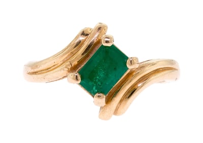 14K YELLOW GOLD EMERALD BYPASS RING.
