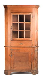 18TH C. CHIPPENDALE PINE CORNER CUPBOARD.: A ca. 1780’s one-piece Chippendale pine corner cupboard in old natural stain. An applied molded top over a single sectional glass door, two interior fixed shelves over one dovetailed drawer, ove