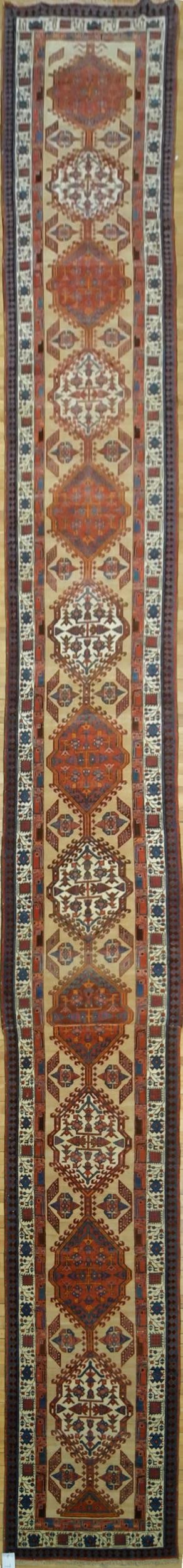 ANTIQUE ORIENTAL RUNNER, 25 FEET.: An antique Oriental runner,12 medallion in red and ivory on camel ground, with white and blue border. 2’11” x 25’2”.