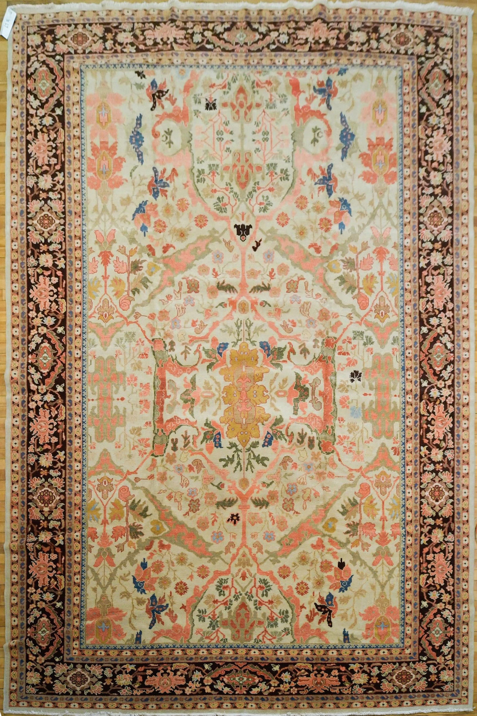 VINTAGE ORIENTAL OUSHAK ROOM SIZE RUG.: A vintage Oriental Oushak room size rug, with ivory field, and salmon, blue and tan floral decoration, with brown border. 9’8” x 12’11”.