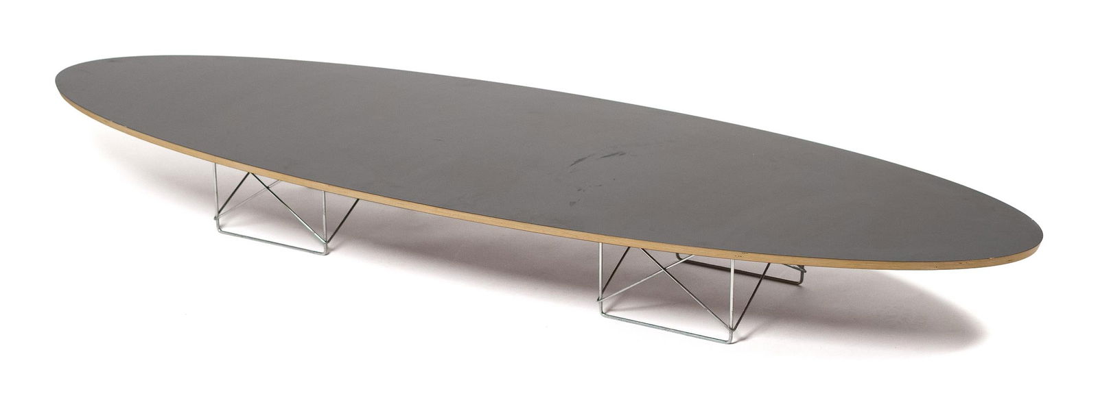 EAMES FOR HERMAN MILLER SURFBOARD COFFEE TABLE.: A contemporary Charles and Ray Eames for Herman Miller surfboard coffee table, a 1994 reissue, made of seven-ply Baltic birch with a laminate top on a zinc plated base. Labeled on underside of top. 9.