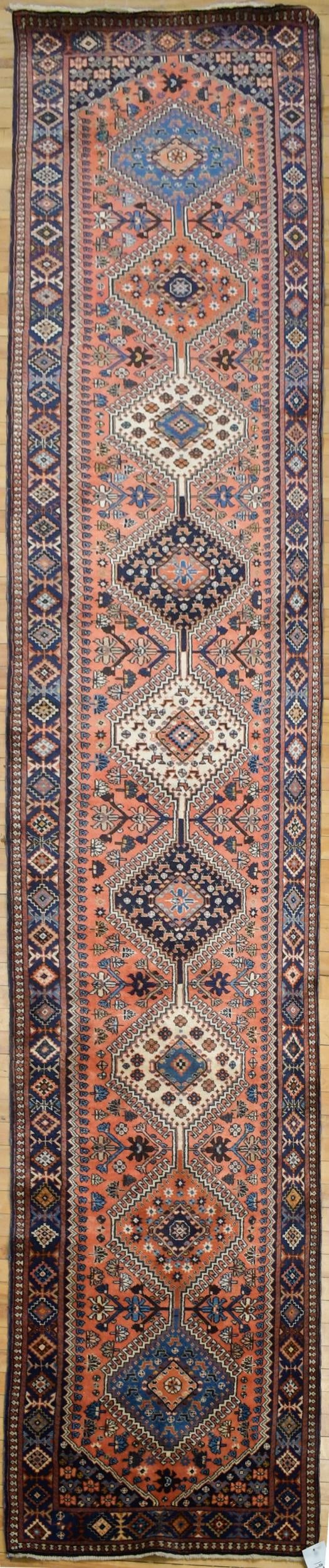 VINTAGE ORIENTAL RUNNER RUG.: A vintage hand woven Oriental Yalemeh runner, with repeating central medallions on red ground. 2’7” x 15’3”.