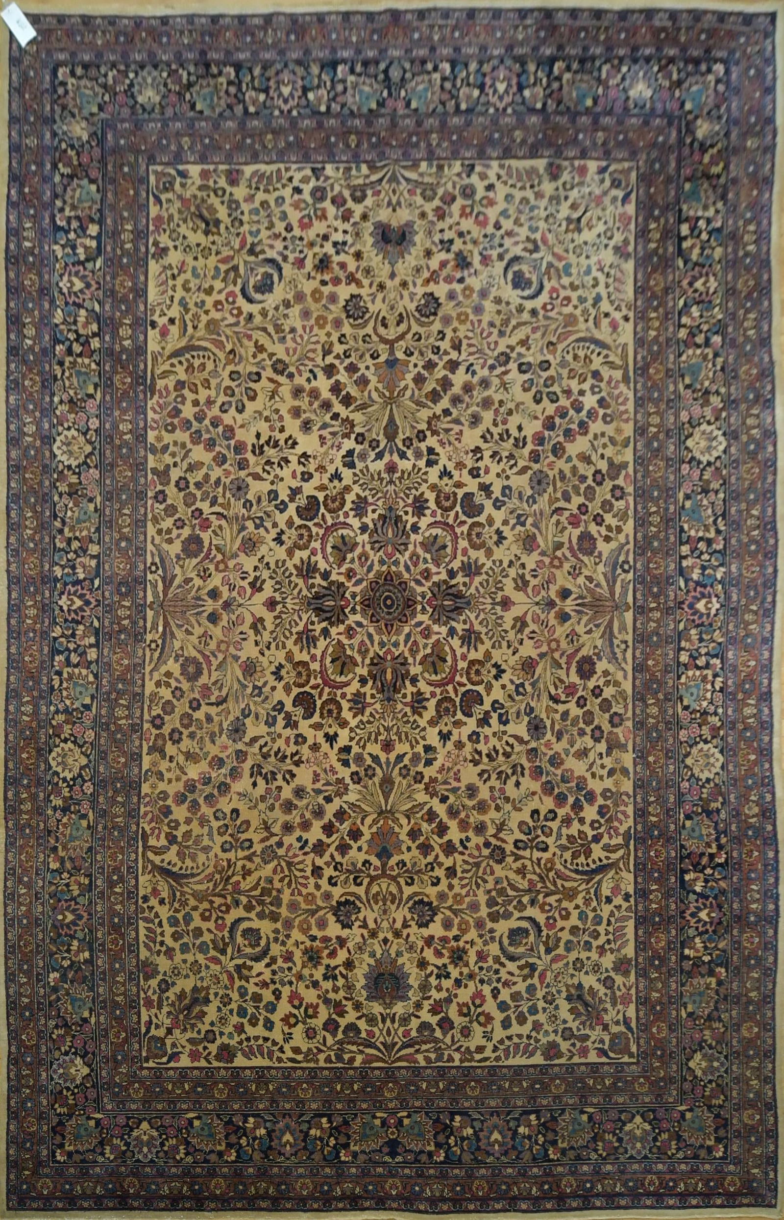 ANTIQUE ROOM SIZE IVORY FIELD ORIENTAL RUG.: A ca. 1930 room size Kermin Oriental rug, with ivory field, with dark blue border. 9’7” x 13’5”.