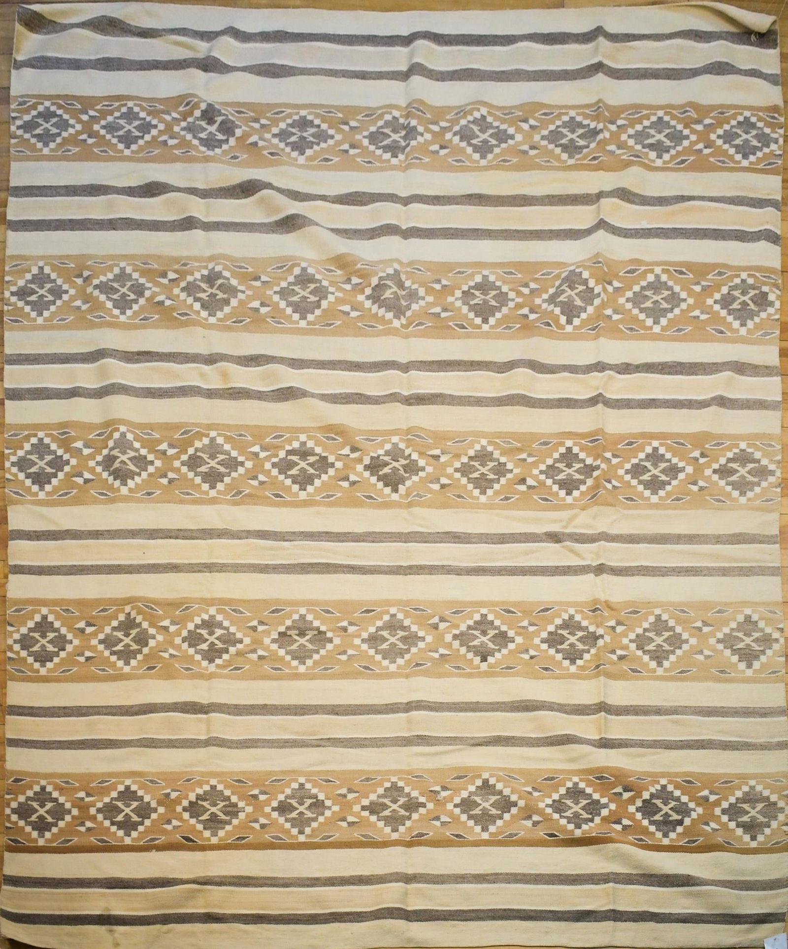 VINTAGE NAVAJO WOVEN BLANKET/RUG: A vintage Navajo woven blanket or rug, in tan, brown, grey and white. With stripes and “X” motifs. 7’10” x 10’1”.