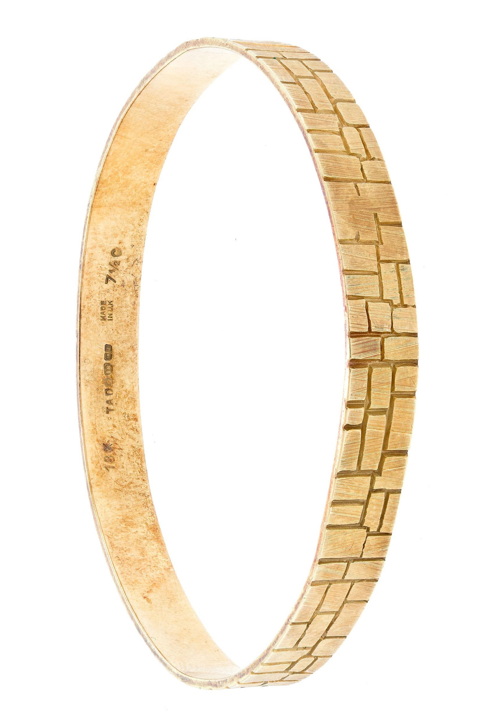 18K GOLD ”LAYERED BRICK” BANGLE BRACELET.: An 18k yellow gold (stamped, British hallmarks), bangle bracelet with layered brick pattern, 7mm wide, 7 1/4” wrist, 19.4 grams.