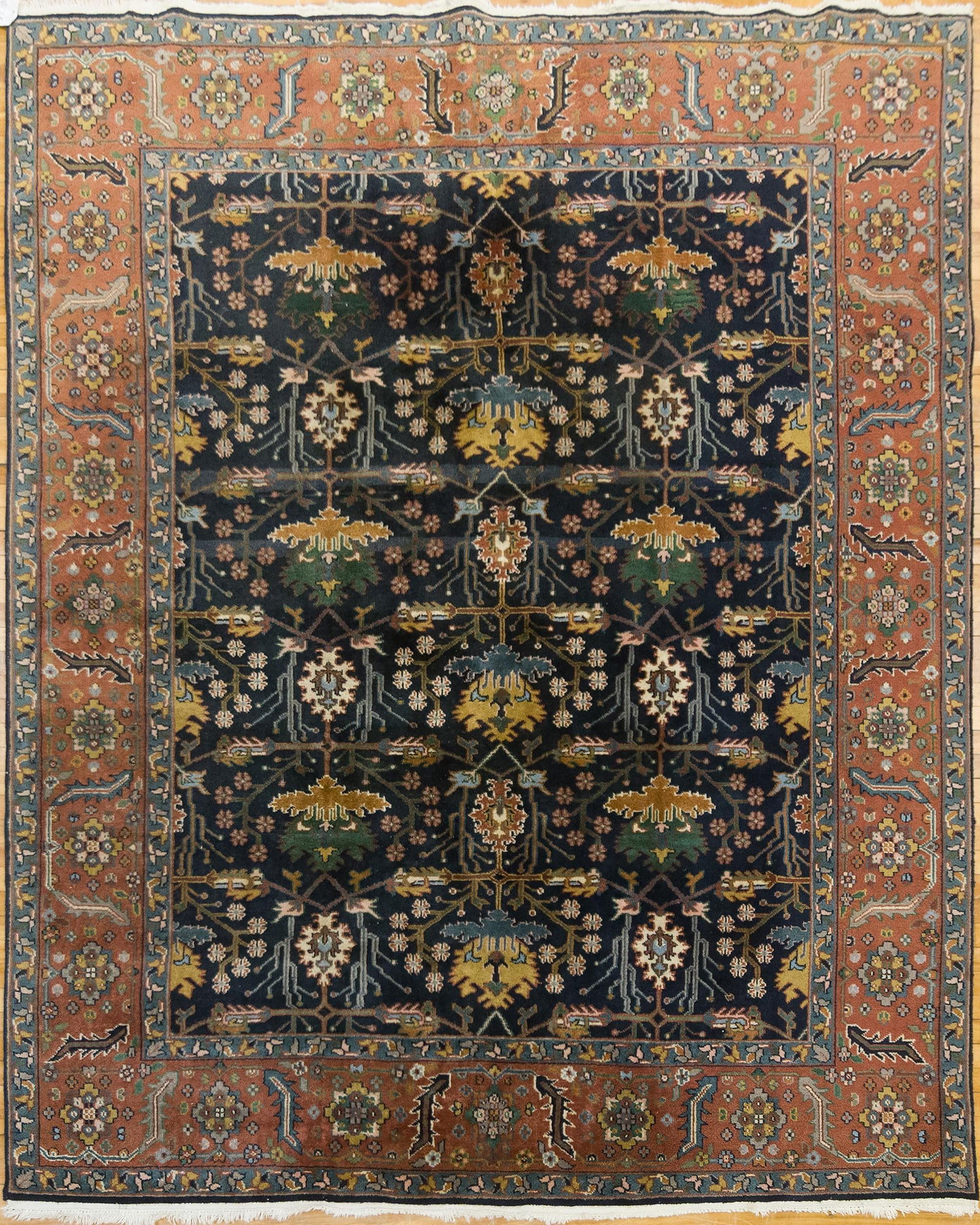 VINTAGE ORIENTAL ROOM SIZE RUG.: A vintage hand woven Oriental room size rug, with midnight blue ground, highlighted with stylized floral and tree motifs, and tan, ivory, light blue, and copper highlights. 7’8” x