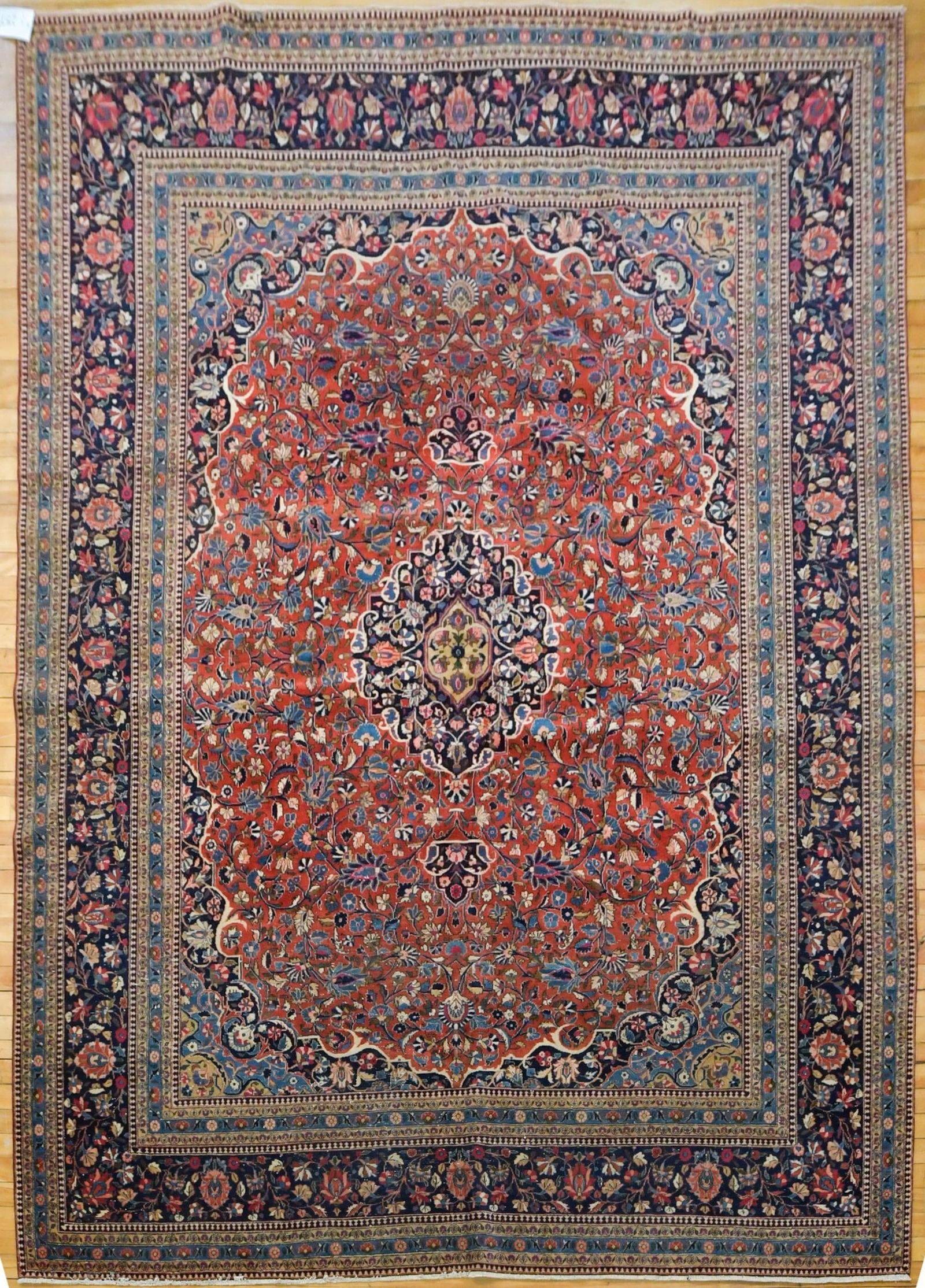 ANTIQUE ORIENTAL KESHAN ROOM SIZE RUG.: A An antique hand woven Oriental Keshan small room size rug, with classic floral central field, on cranberry red ground, and tan, blue, ivory. 7’9” x 10’.