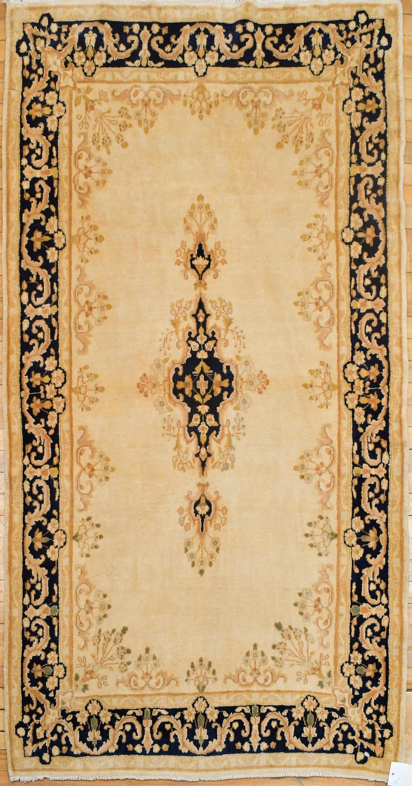 VINTAGE ORIENTAL KERMAN SCATTER RUG.: A vintage Oriental Kerman ivory field area rug, with dark blue central medallion and border. 4’10” x 6’9”