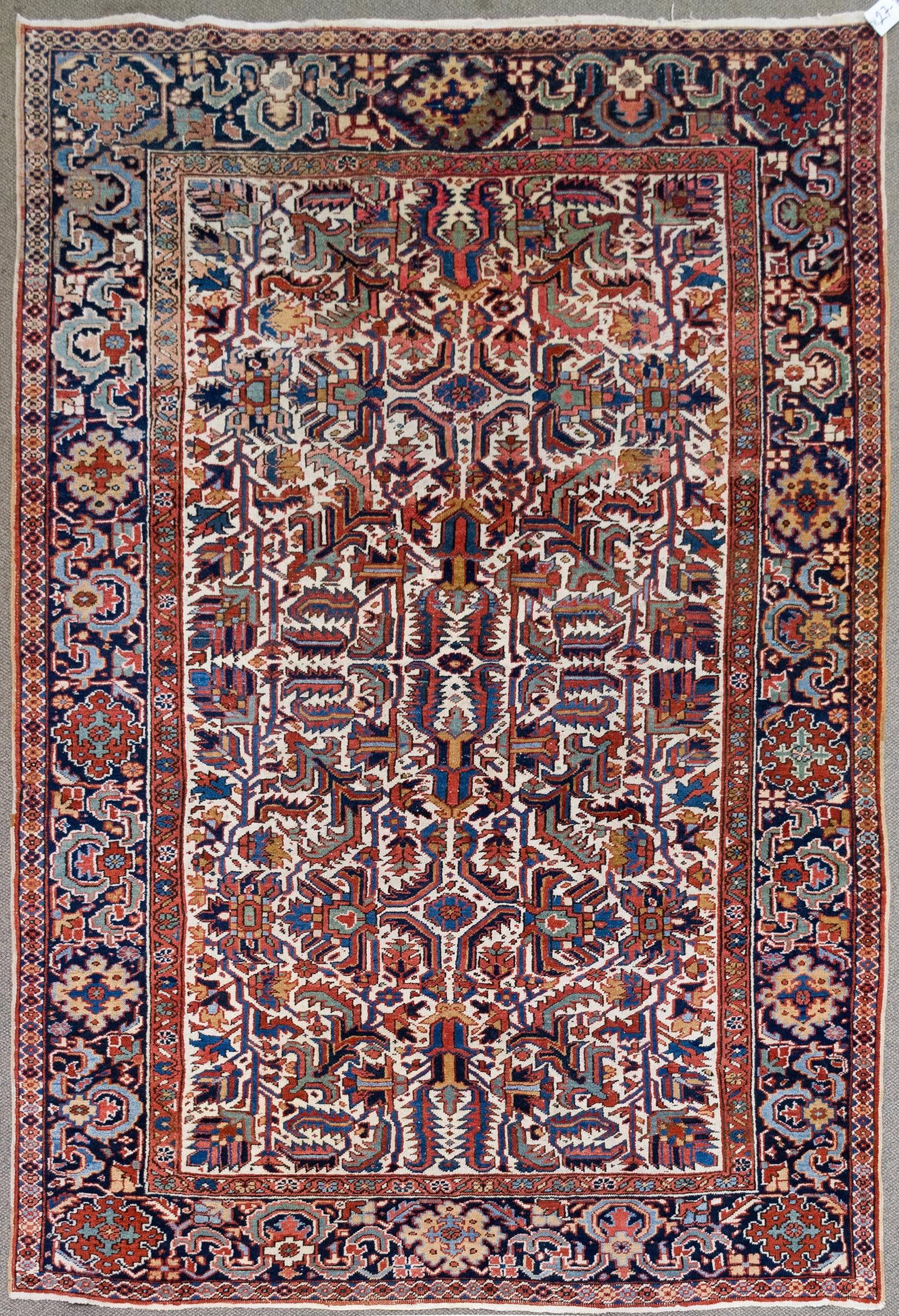 ANTIQUE ORIENTAL HERIZ ROOM SIZE RUG.: A hand woven antique Oriental room size Heriz rug with unusual ivory ground, highlighted with teal, blue, tan and green. 7’ x 10’3”.