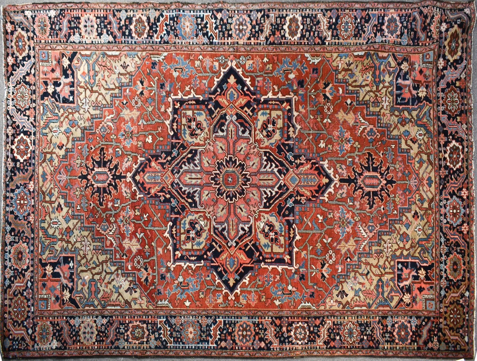 GOOD ANTIQUE ORIENTAL HERIZ ROOM SIZE RUG.: A good 1920s hand woven Oriental Heriz room size rug with a large central medallion, red ground and highlighted with blues, tan, ivory and pink. 8’ x 11’7”.