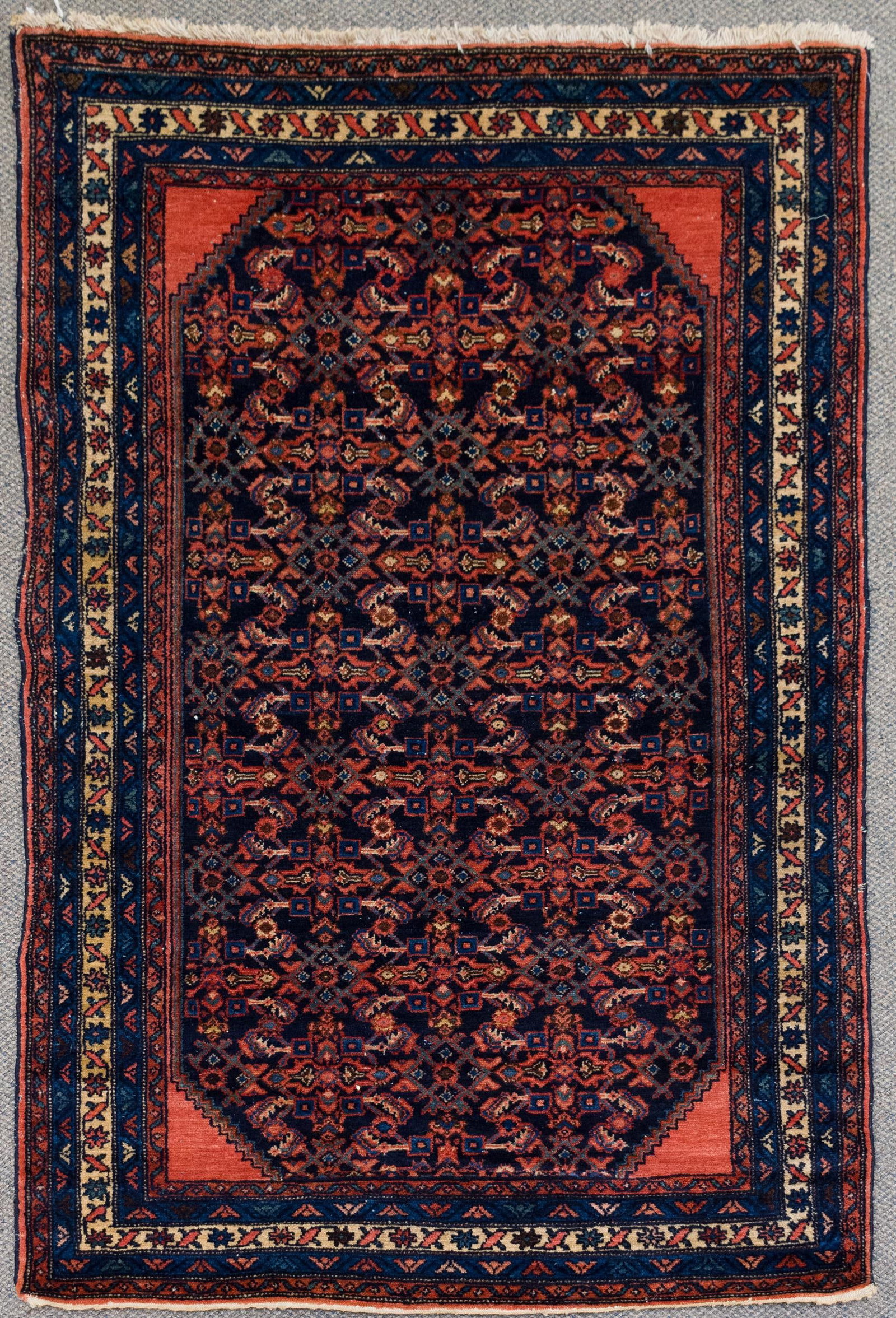 ANTIQUE ORIENTAL SENNEH SCATTER RUG.: An antique hand woven Oriental Senneh scatter rug with an ivory and blue border surrounding a complex multi-color field. 3'3” x 5'.