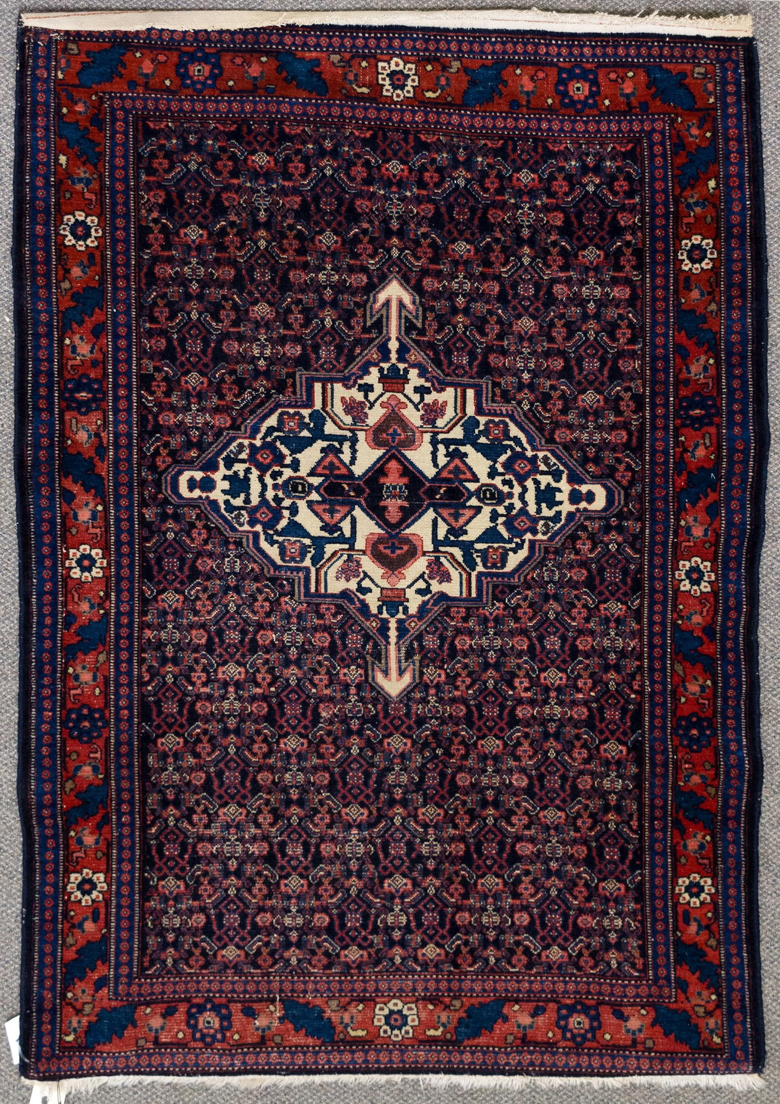 ANTIQUE ORIENTAL SENNEH SCATTER RUG.: An antique hand woven Oriental Senneh scatter rug with complex and intricate weaving in blue, red and ivory. 3'5” x 5'