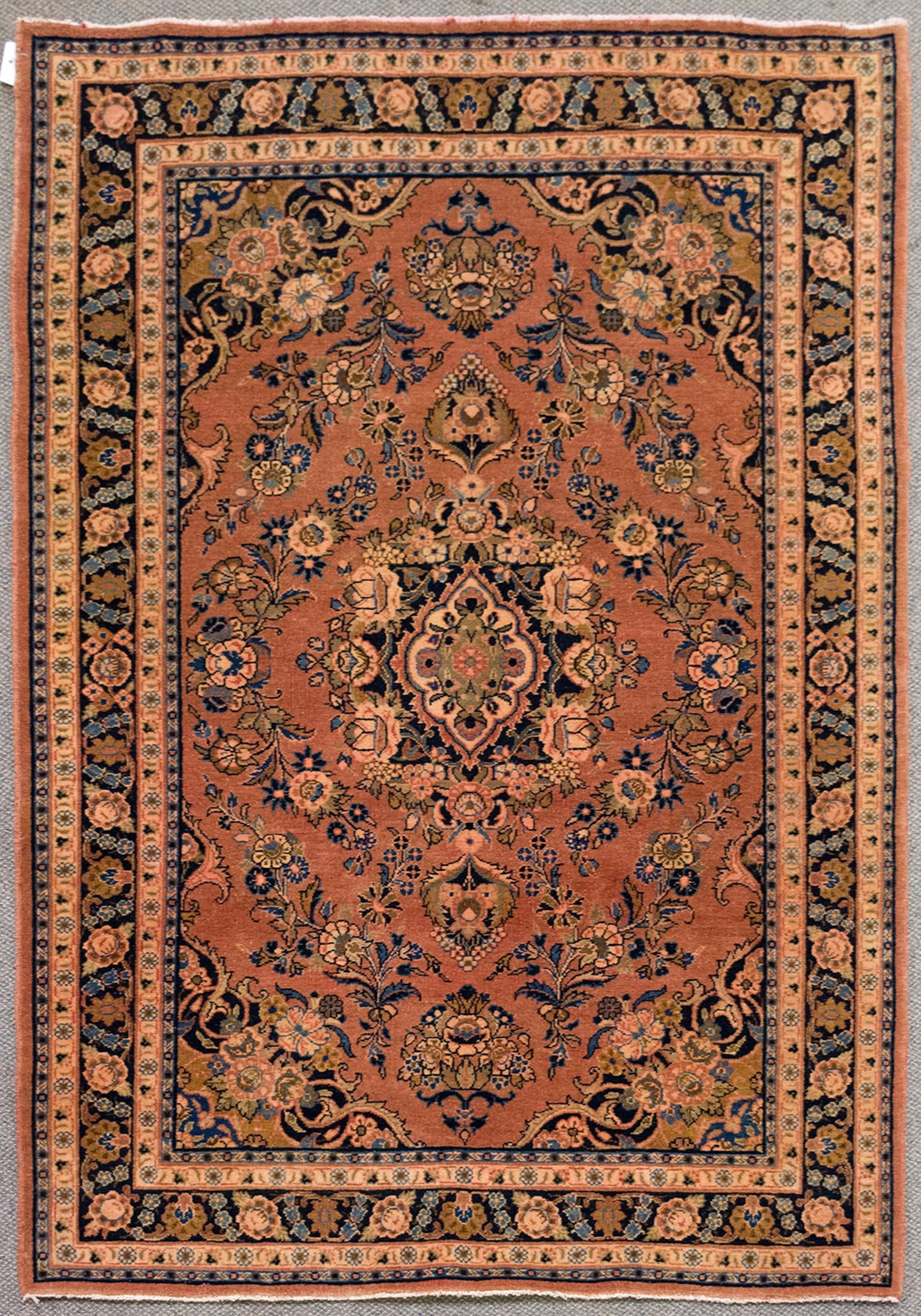 VINTAGE ORIENTAL AREA RUG.: A vintage hand woven Oriental area rug with a central medallion on soft red ground, highlighted with cobalt blue. 4’7” x 6’7”.