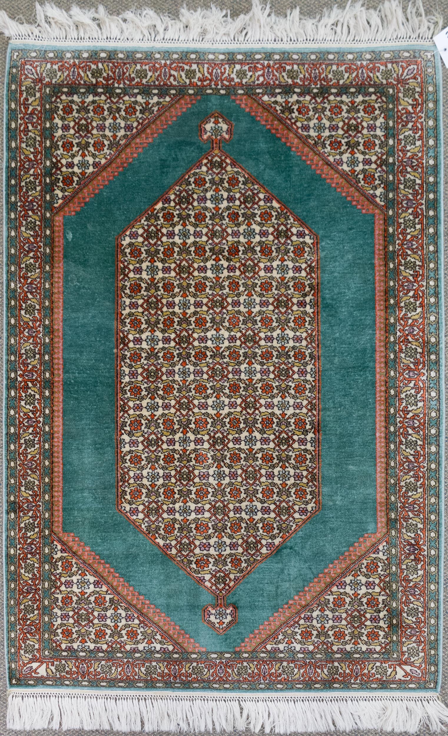 VINTAGE ORIENTAL SILK SCATTER RUG.: A vintage hand woven Oriental silk scatter rug with green ground, highlighted in red and ivory. 3’1” x 4’10”.