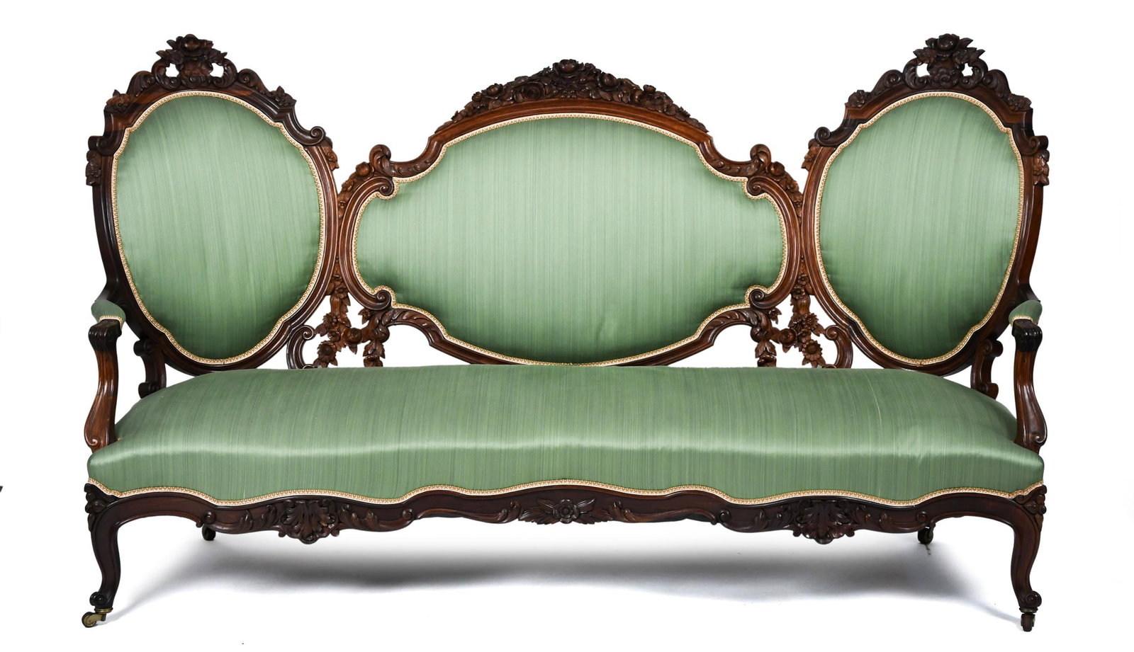 FINE VICTORIAN ROSEWOOD SOFA.: A fine ca. 1860 New York Victorian rosewood triple back sofa, with wonderfully detailed floral carved crests, open arm supports with a beautifully carved apron, on cabriole legs with caster feet,