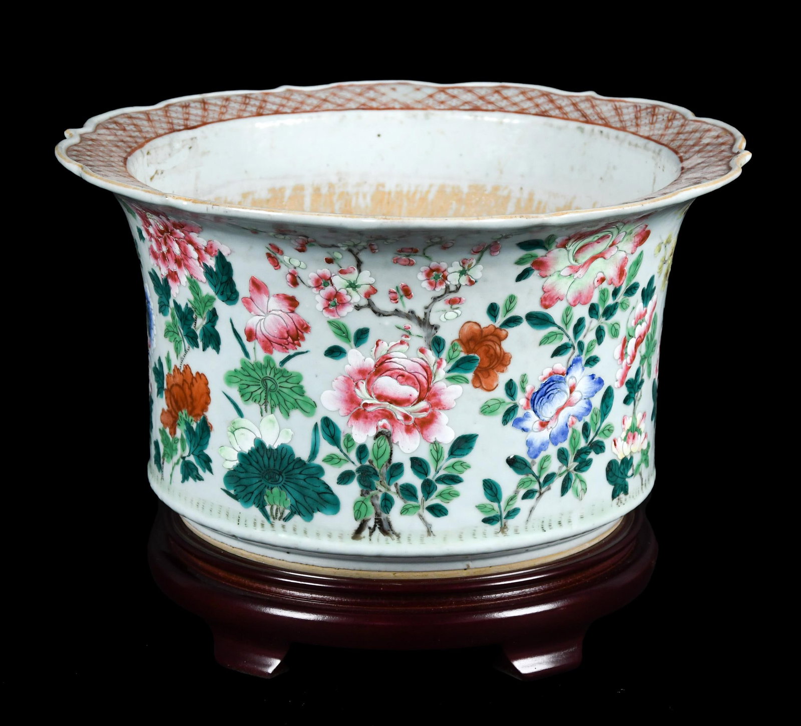 ANTIQUE CHINESE PORCELAIN FAMILLE ROSE JARDINIERE.: An antique Chinese porcelain Famille Rose jardinere, with floral decoration, on wooden stand. 9”H x 16” dia.