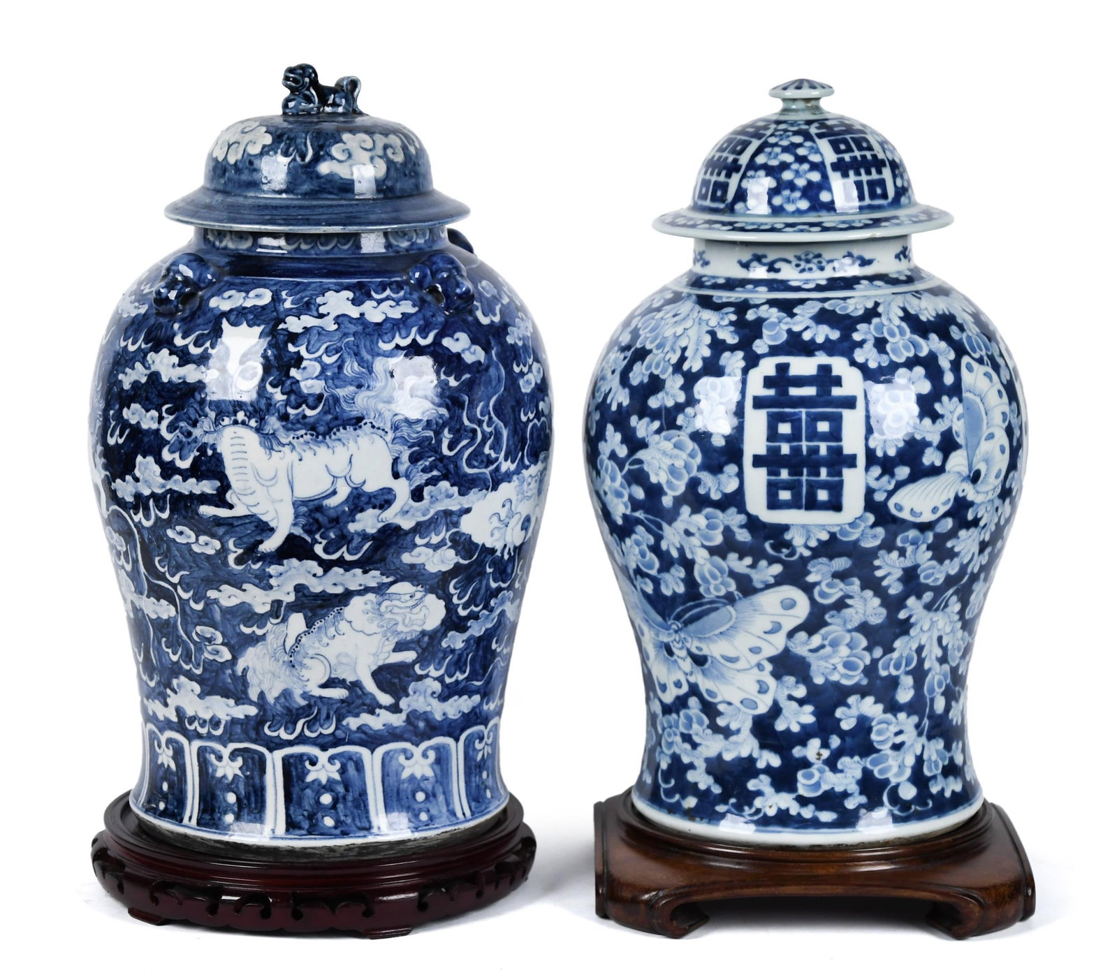 TWO CHINESE BLUE AND WHITE PORCELAIN TEMPLE JARS.: Two Chinese porcelain lidded temple jars, in blue and white glaze, both on custom wooden stands. One example with foo lions 18”H, other with butterflies 17”H.