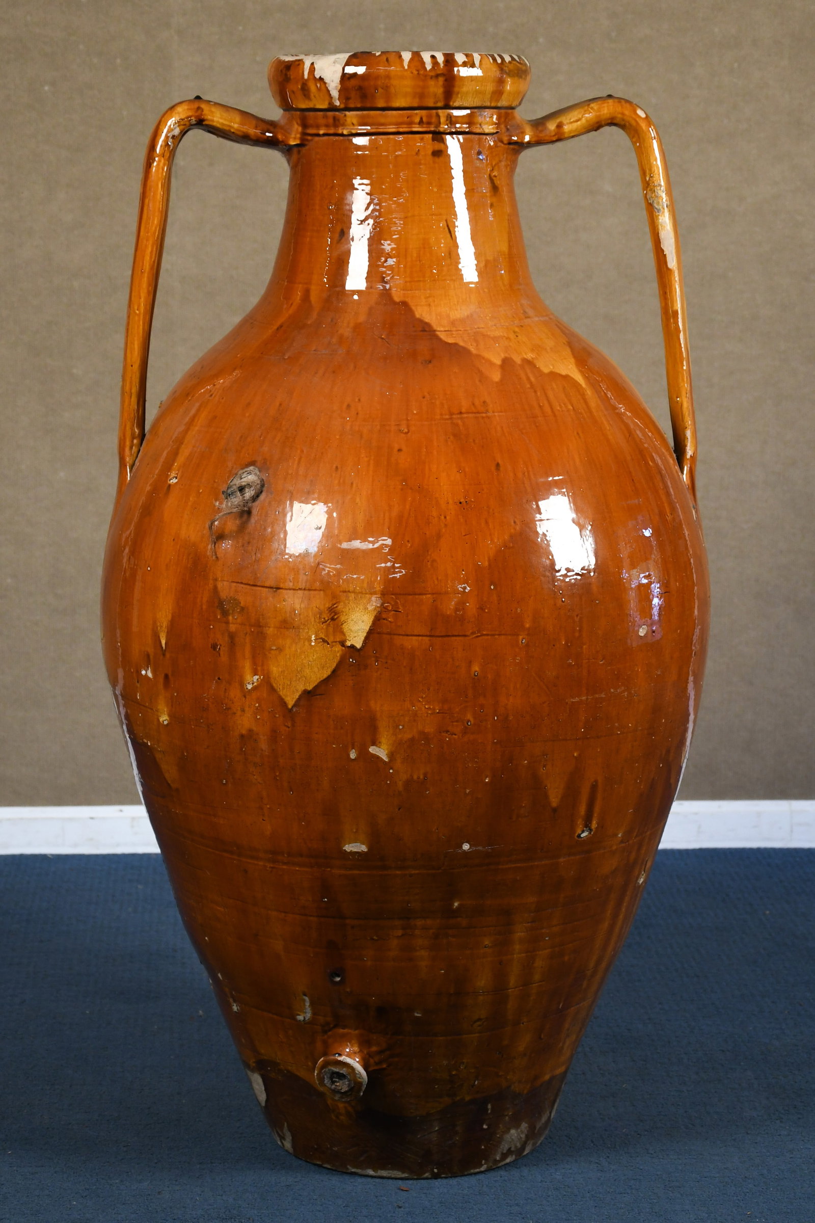 ANTIQUE ITALIAN OLIVE OIL AMPHORA (2 OF 3).: A large antique Italian terracotta olive oil amphora, in ochre glaze, with spigot at bottom. 53”H x 28”W.