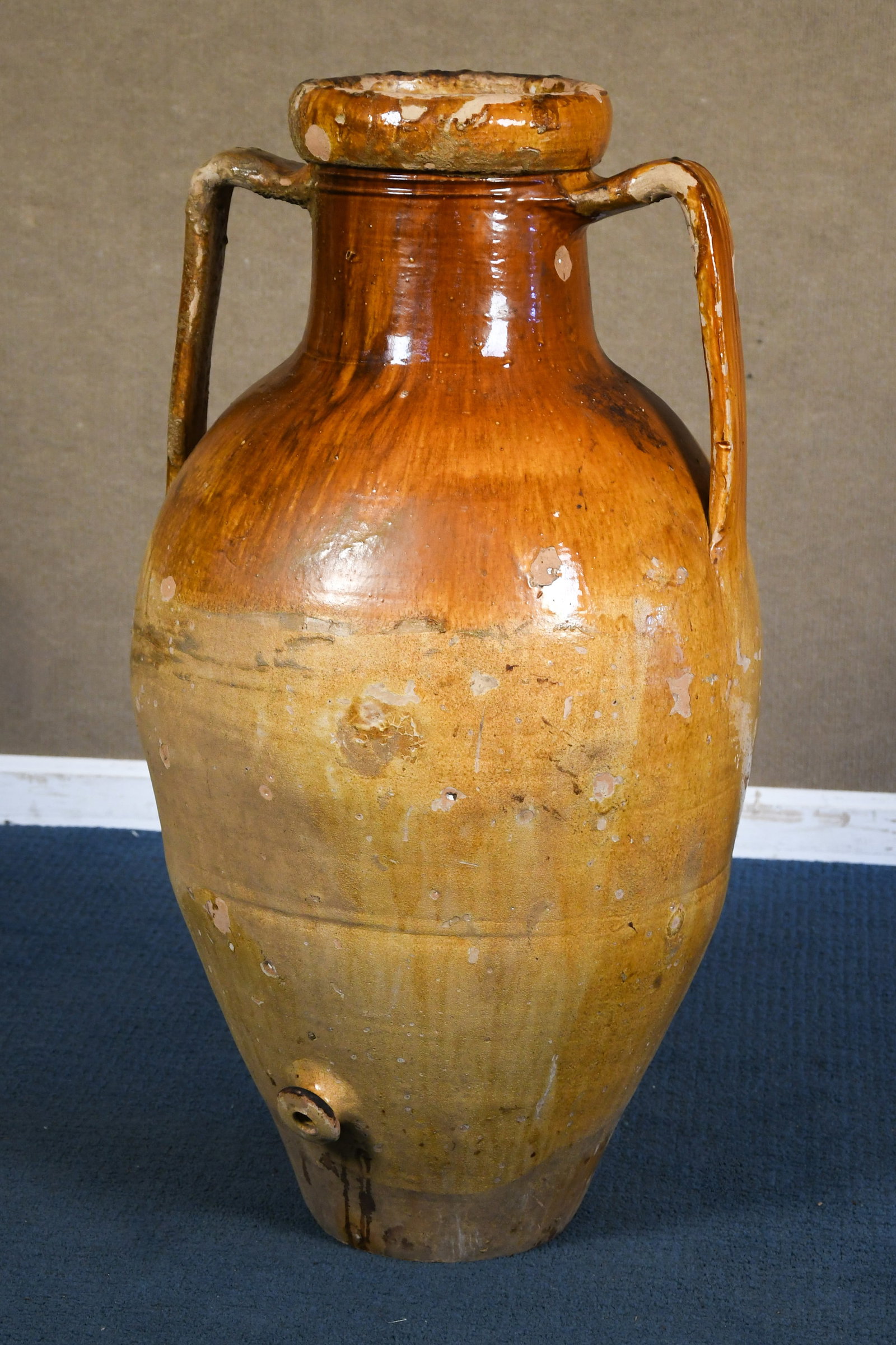 ANTIQUE ITALIAN OLIVE OIL AMPHORA (3 OF 3).: A large antique Italian terracotta double handled olive oil amphora, in ochre glaze, with spigot at bottom. 37”H x 17”W.