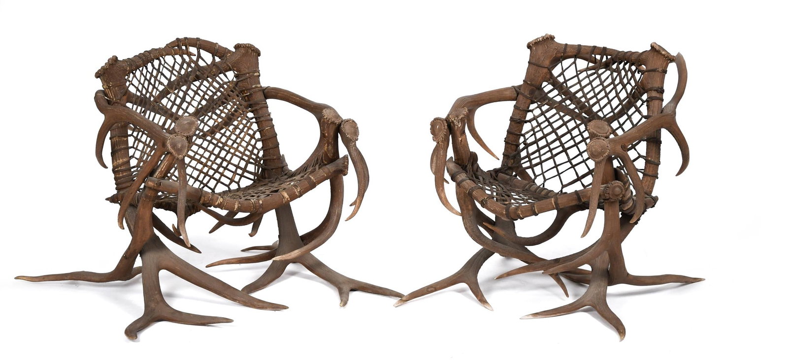 PR. ANTIQUE ELK ANTLER ARM CHAIRS.: A pair of early 20th C. German Black Forest elk antler arm chairs, with woven sinew seats and backs. 30”H x bases 35”W x 33”D.