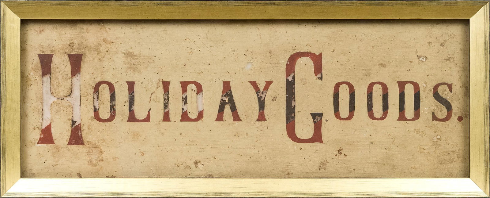 ANTIQUE HOLIDAY GOODS GLASS SIGN.: A ca. 1900 framed sign, reading HOLIDAY GOODS, reverse painted on glass in a later 20th C. gilt frame. Overall 8.25” x 20.5”. Provenance: from the lifelong, curated collection of Kathy