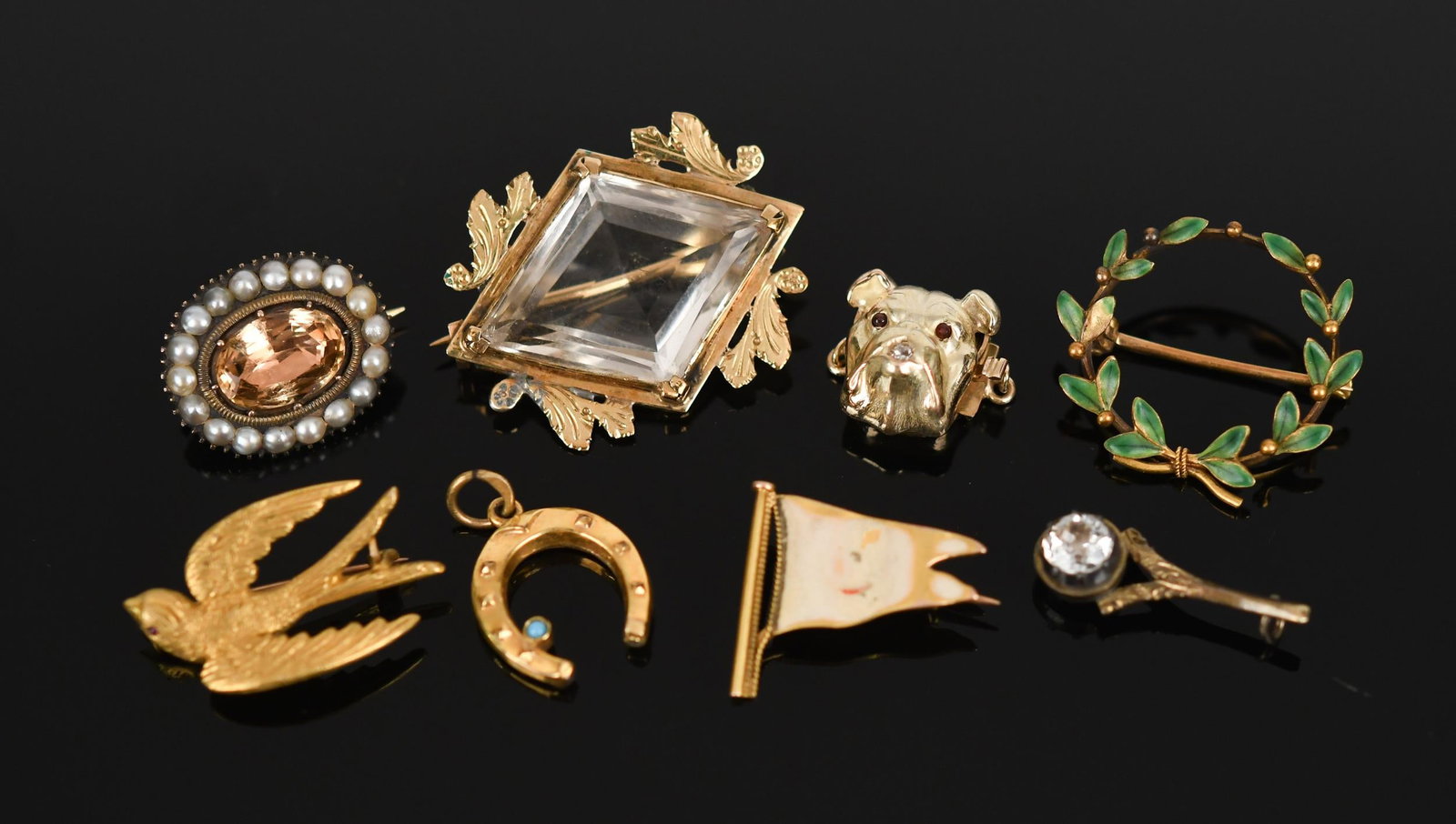 ANTIQUE GOLD PINS, HORSESHOE CHARM & BULLDOG CLASP.: Antique, yellow gold (stamped or tested) jewelry, including: four, 14k pins, step cut quartz, approx. 10 ct., 1 1/4” long, sparrow w/ ruby eye, enamel flag (chips) and green laurel wreath