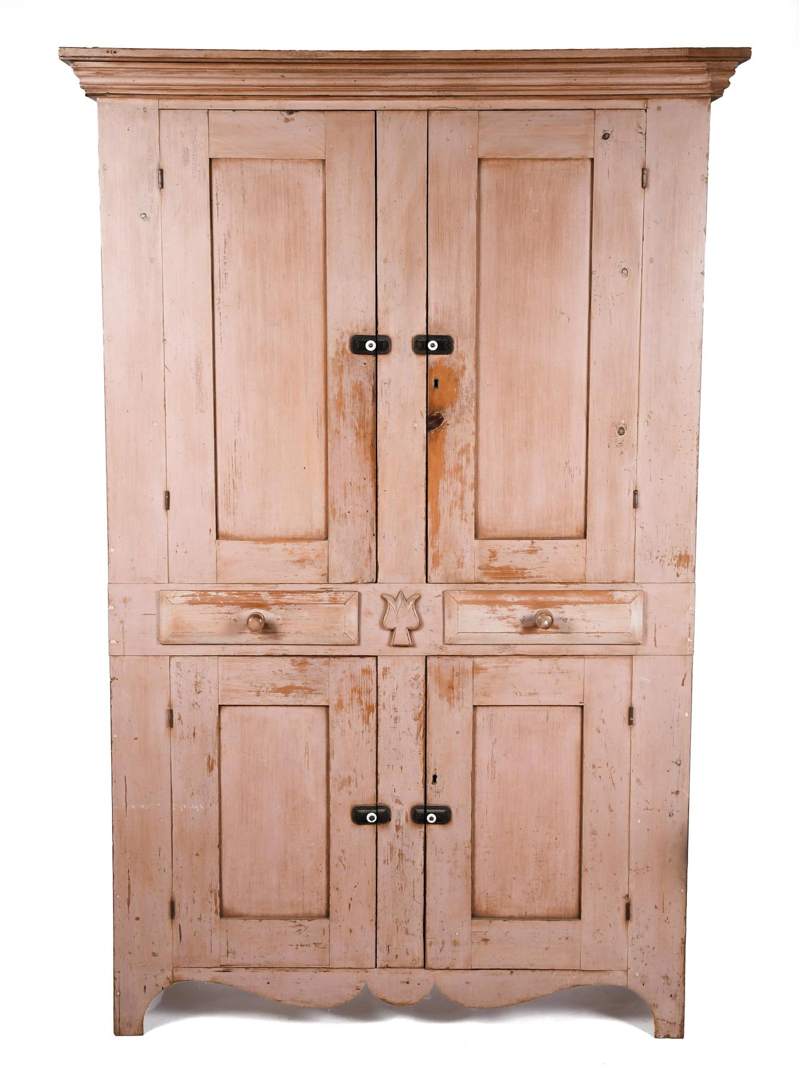 CHOICE 19TH C. SALMON PAINTED TULIP CUPBOARD.: A choice 19th C. floor cupboard in old salmon paint with unique tulip carving. A double step applied molding over two panel doors, the interior with two fixed shelves, below are two drawers flanking
