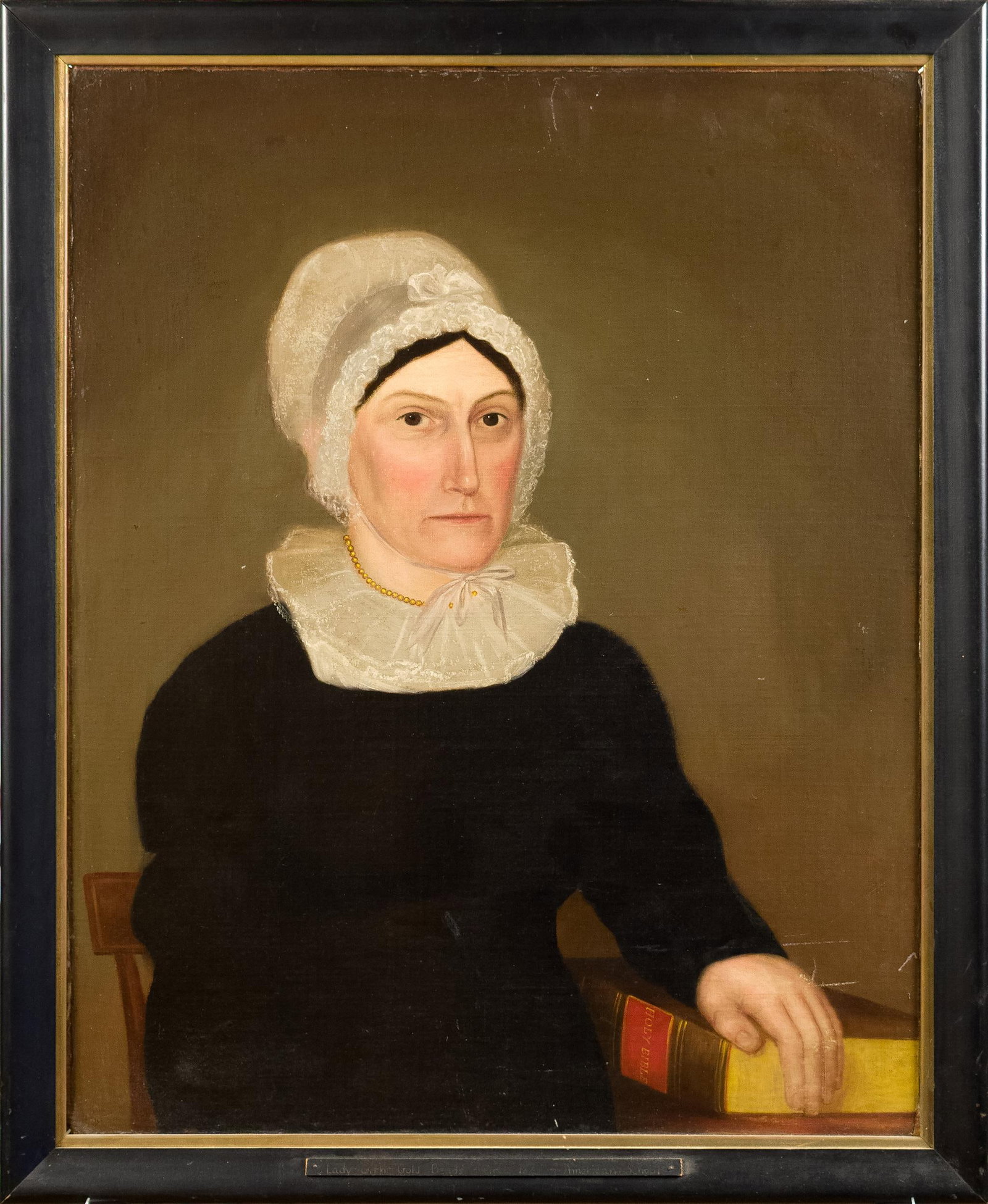 19TH C. AM. SCHOOL OIL, ATTRIB. JOHN BREWSTER.: A ca. 1815 American School oil on canvas, attributed to John Brewster. A 3/4 length portrait of a seated woman wearing a bonnet with lace trim, with left hand placed on the Holy Bible. Image