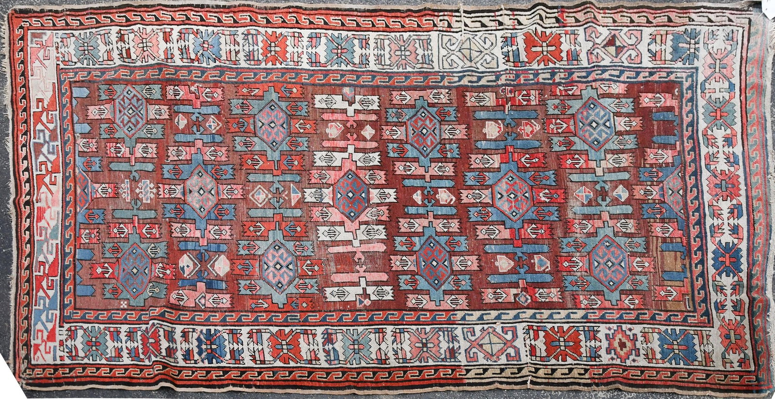 ANTIQUE ORIENTAL AREA RUG.: An antique Oriental hand-woven area rug with brown center ground and pink, blue and ivory designs and borders. 6' x 9'8”.