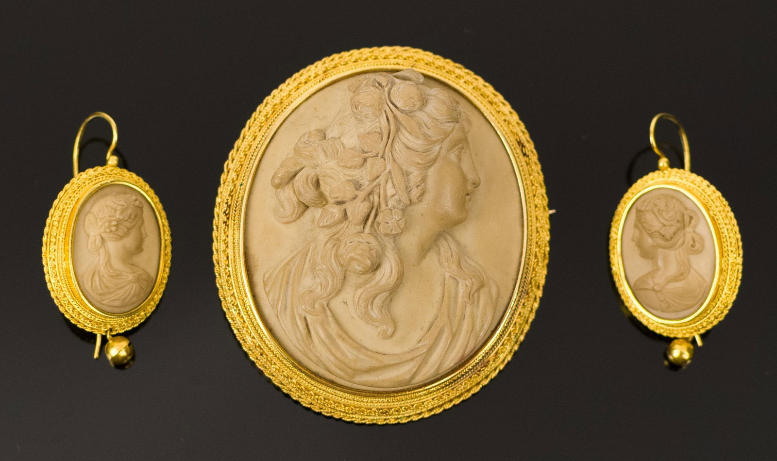 VICTORIAN 18K GOLD LAVA CAMEO PIN & EARRINGS.: A Victorian, 18k yellow gold (tested), lava stone cameo, pin, 2 1/4” x 1 7/8” dim., and French wire earrings, 1 1/2” long, 39.6 grams gross weight.