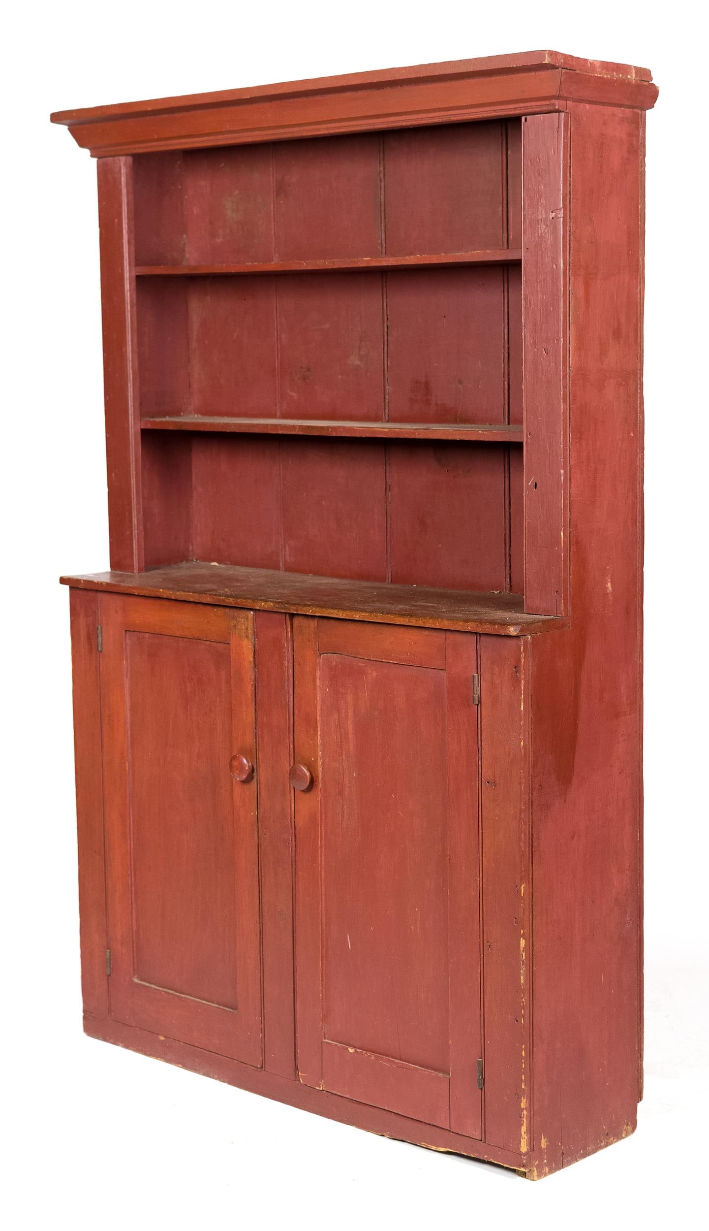 EARLY 19TH C. NEW ENGLAND SETBACK PAINTED CUPBOARD.: A ca. 1820 New England set-back open top one piece cupboard in old red paint. Applied molded cornice open top with two fixed shelves over two panel doors with. Wood knobs base set flush to the floor, 