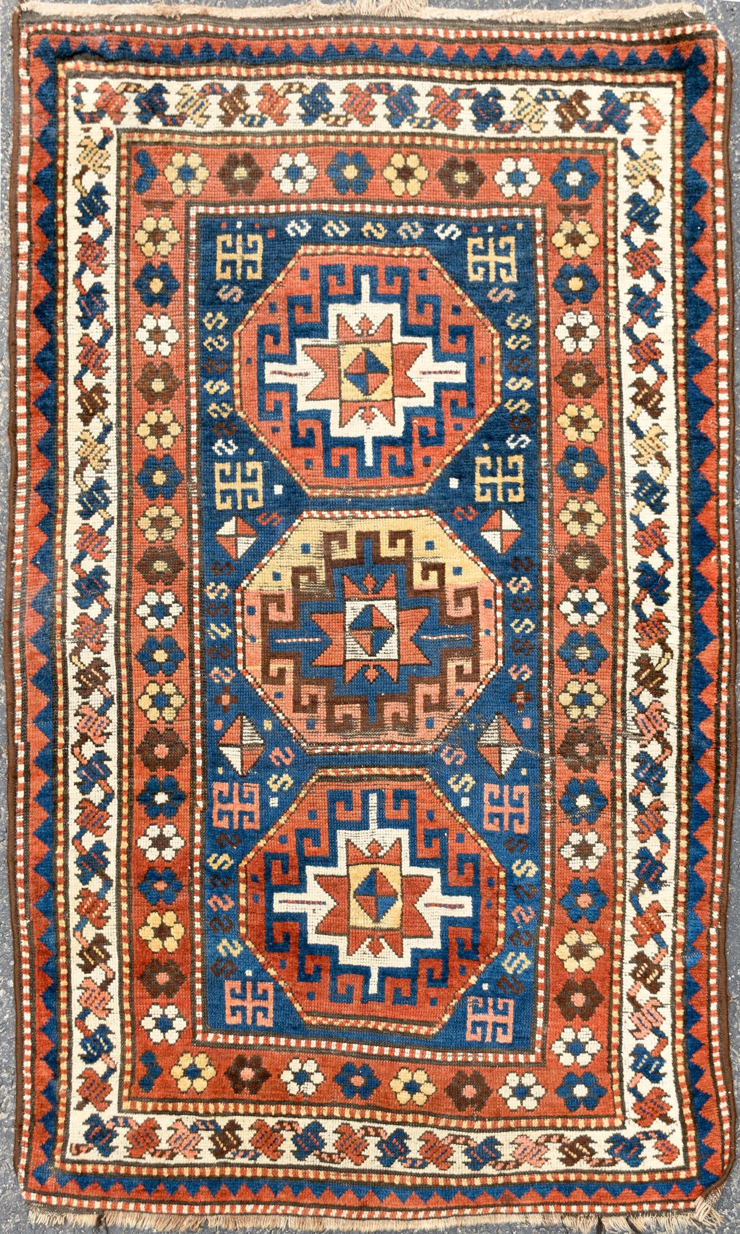 ANTIQUE ORIENTAL AREA RUG.: An antique Oriental hand-woven area rug with three octagonal designs in center with blue ground highlighted with brick red and ivory, concentric borders in red, ivory and red/blue. 3'9” x 5'11&#