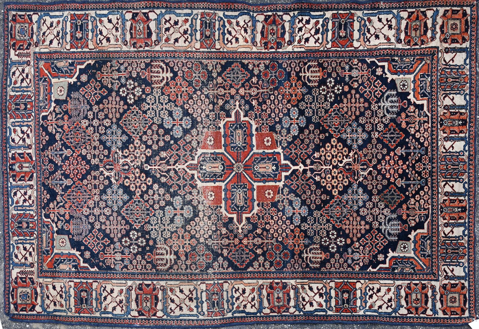 ANTIQUE ORIENTAL AREA RUG.: An antique Oriental hand-woven area rug with blue ground highlighted with brownish red and ivory. 4’5” x 6’11”.