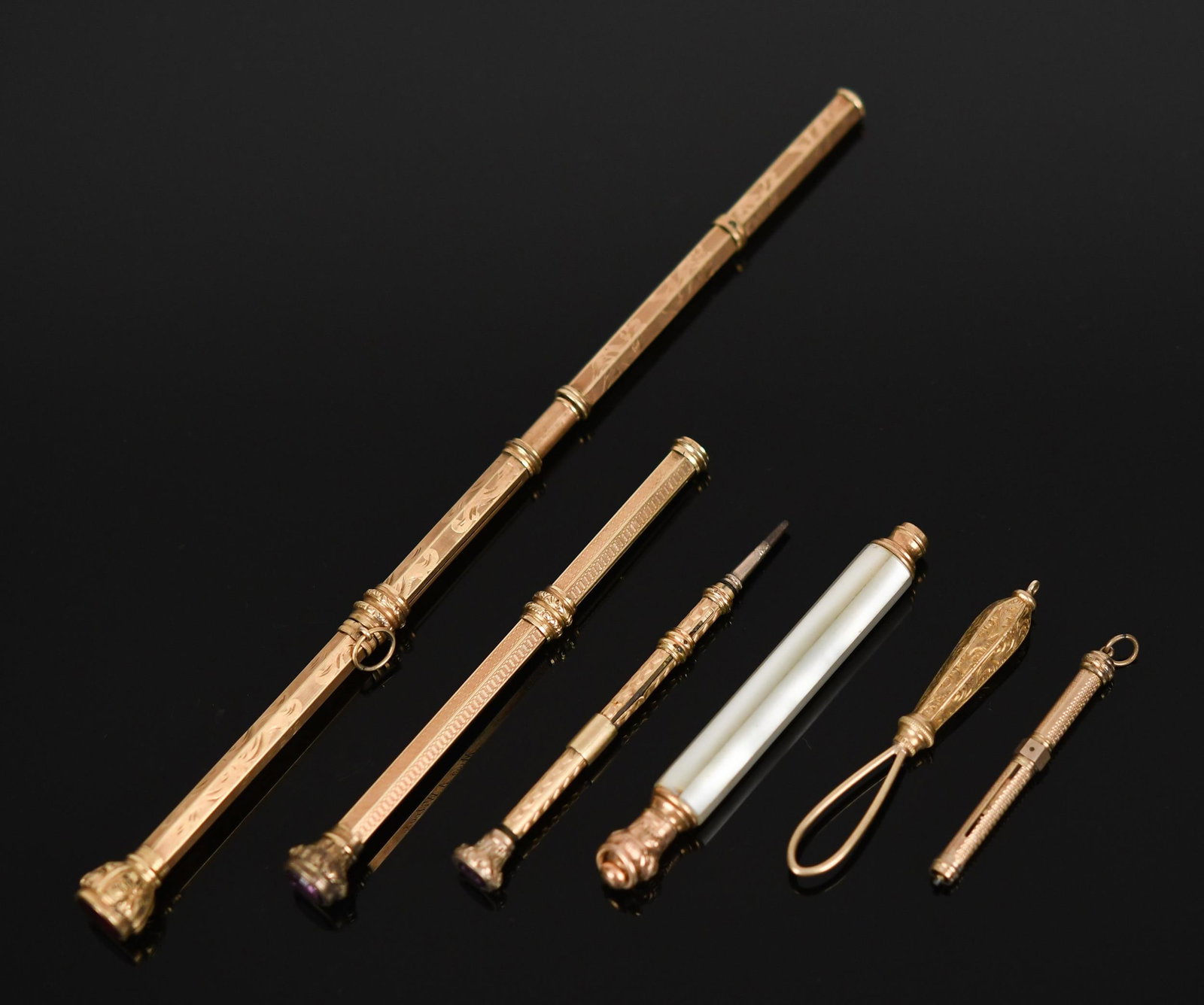 VICTORIAN GOLD-FILLED RETRACTABLE PENCILS.: Five, Victorian, gold-filled, retractable pencils, mother-of-pearl, red and purple synthetic stone or glass ends and gold-filled hook or scoop tool, 1 1/2” to 6 1/2” long.