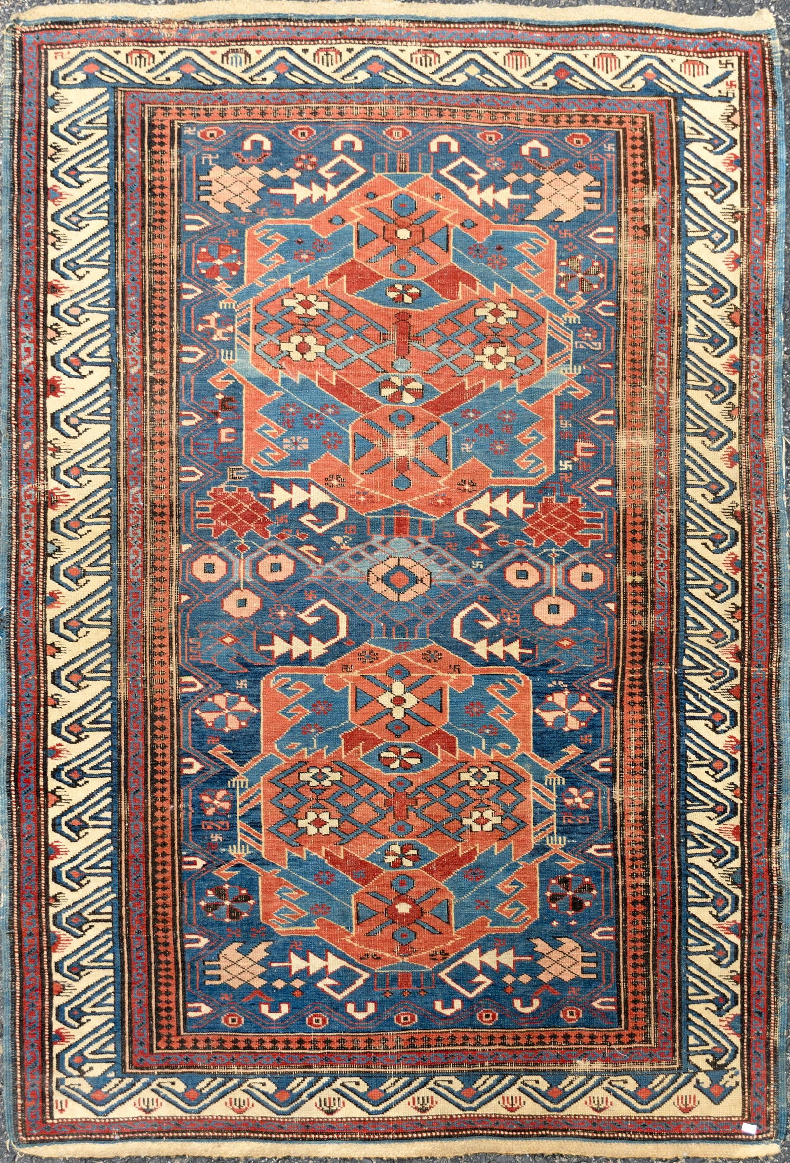 ANTIQUE ORIENTAL AREA RUG.: An antique Oriental hand-woven area rug with center blue ground and two red designs highlighted with brownish red and ivory and bordered with reds and ivory. 3'8” x 5'7”. Provenance: the