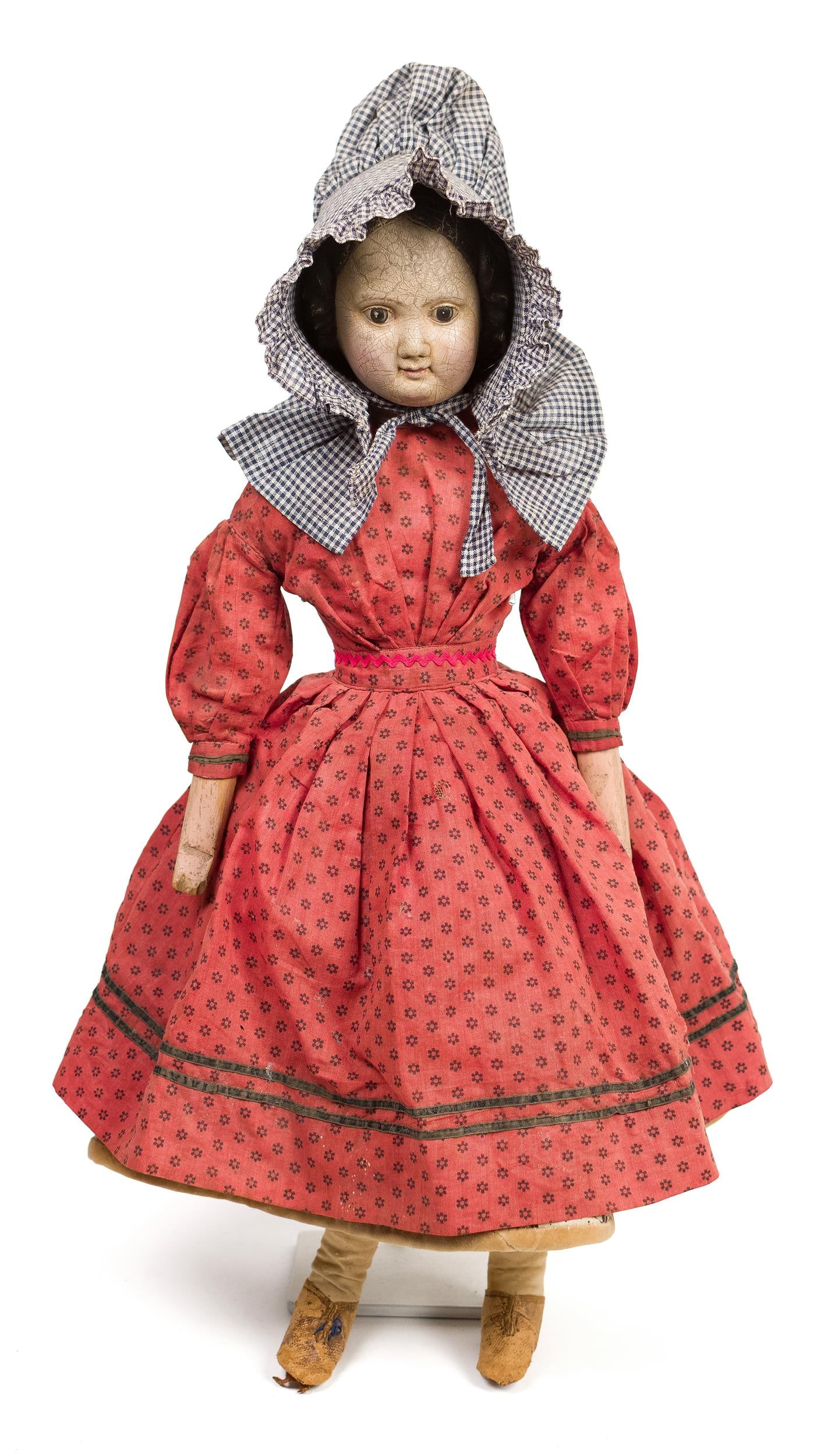 19TH C. RUBBER HEAD DOLL.: An unusual ca. 1870 rubber head child’s doll with blue and white bonnet and red dress, doll with an attached card describing provenance Joan & Larry Kindler, 20”H. Provenance: from the