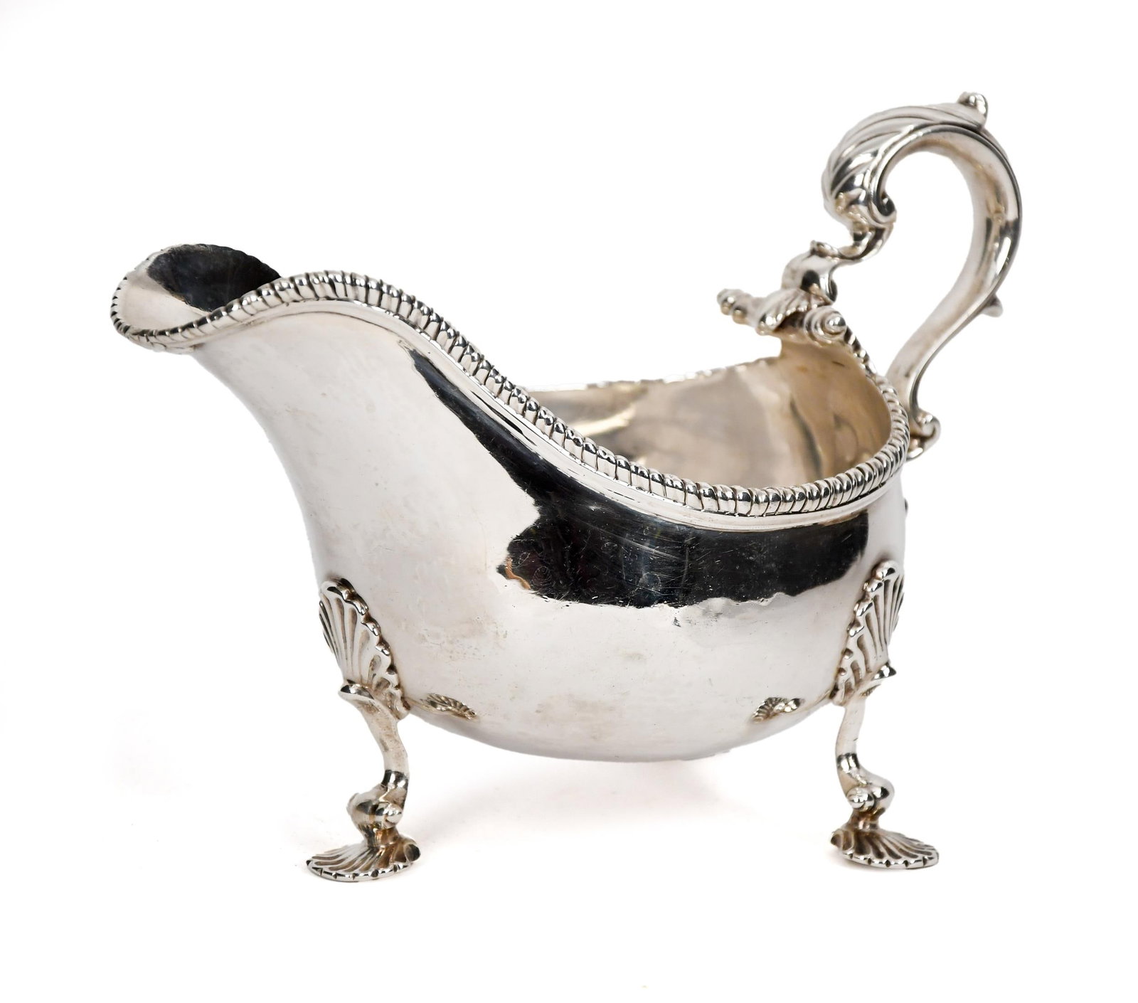 ANTIQUE ENGLISH STERLING GRAVY/SAUCE BOAT.: A 19th C. English sterling gravy/sauce boat with acanthus decorated handle and trifid legs, and gadrooned rim, with Lion Passant, pineapple, and G.S. cartouches. 12.10 oz t. 5.25”H x