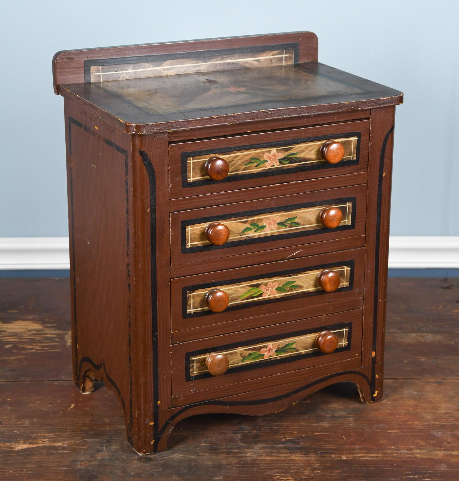 ANTIQUE MINIATURE PAINTED CHEST.: An antique miniature doll’s painted wood chest, with four drawers and deck top, top and drawer front with faux marble painting and floral decoration, on a red grain painted ground. 20”H x