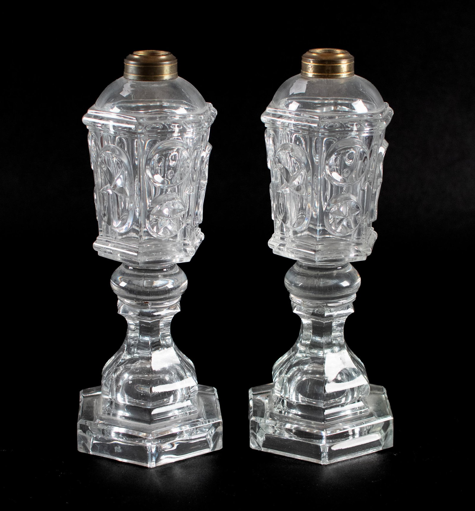 PR. 19TH C. STAR & PUNTY WHALE OIL LAMPS.: Pair of 19th C. glass whale oil lamps, pressed glass 'Star and Punty' pattern with metal collars and hexagonal base. 10.75”H x 4.5” dia.