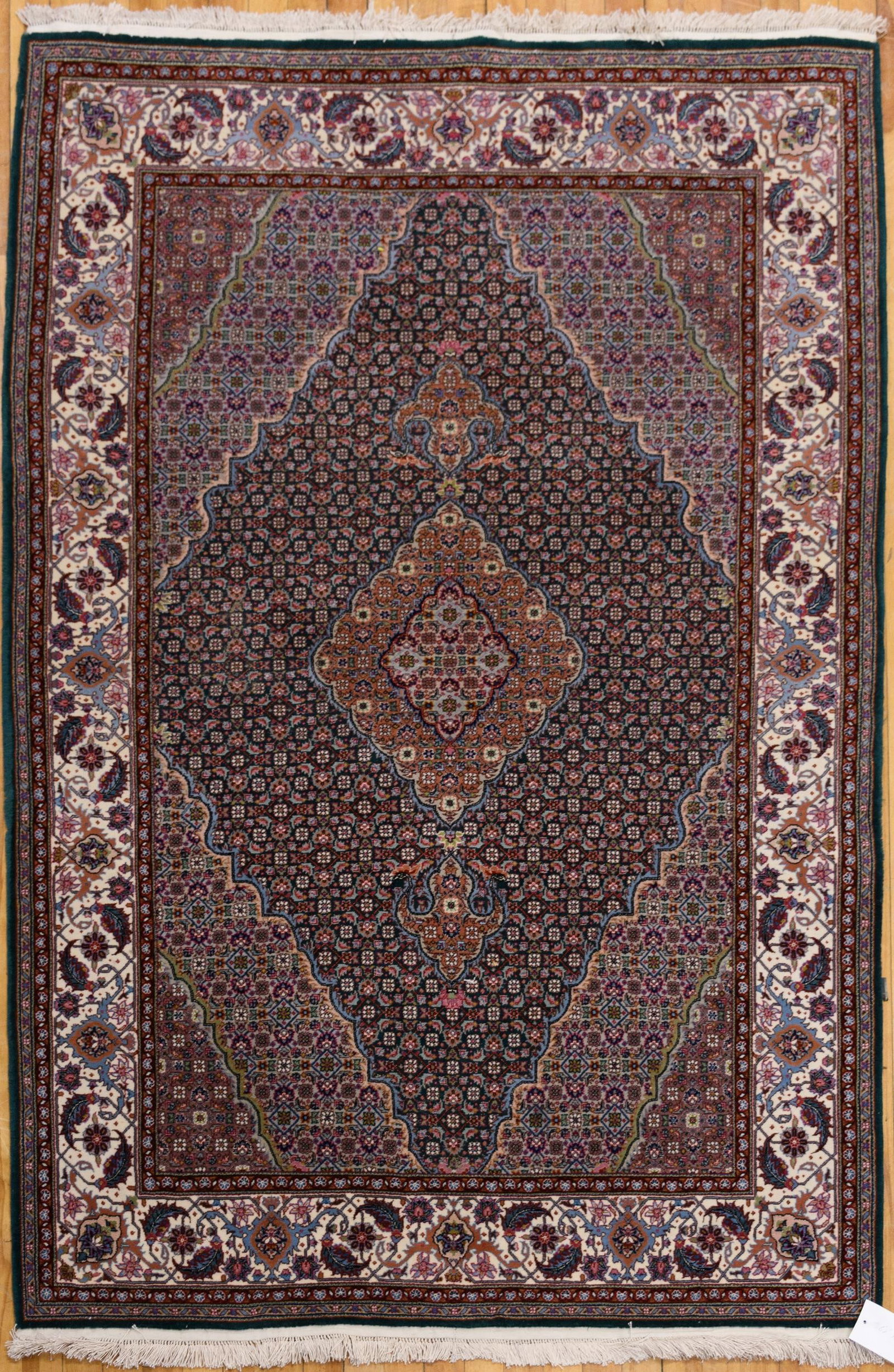 FINE PERSIAN GREEN GROUND ORIENTAL RUG.: A contemporary, finely woven Persian oriental rug, the dark green field centered by a lobed salmon and ivory medallion with pendants, flanked by conforming corner spandrels, within an ivory palmette a