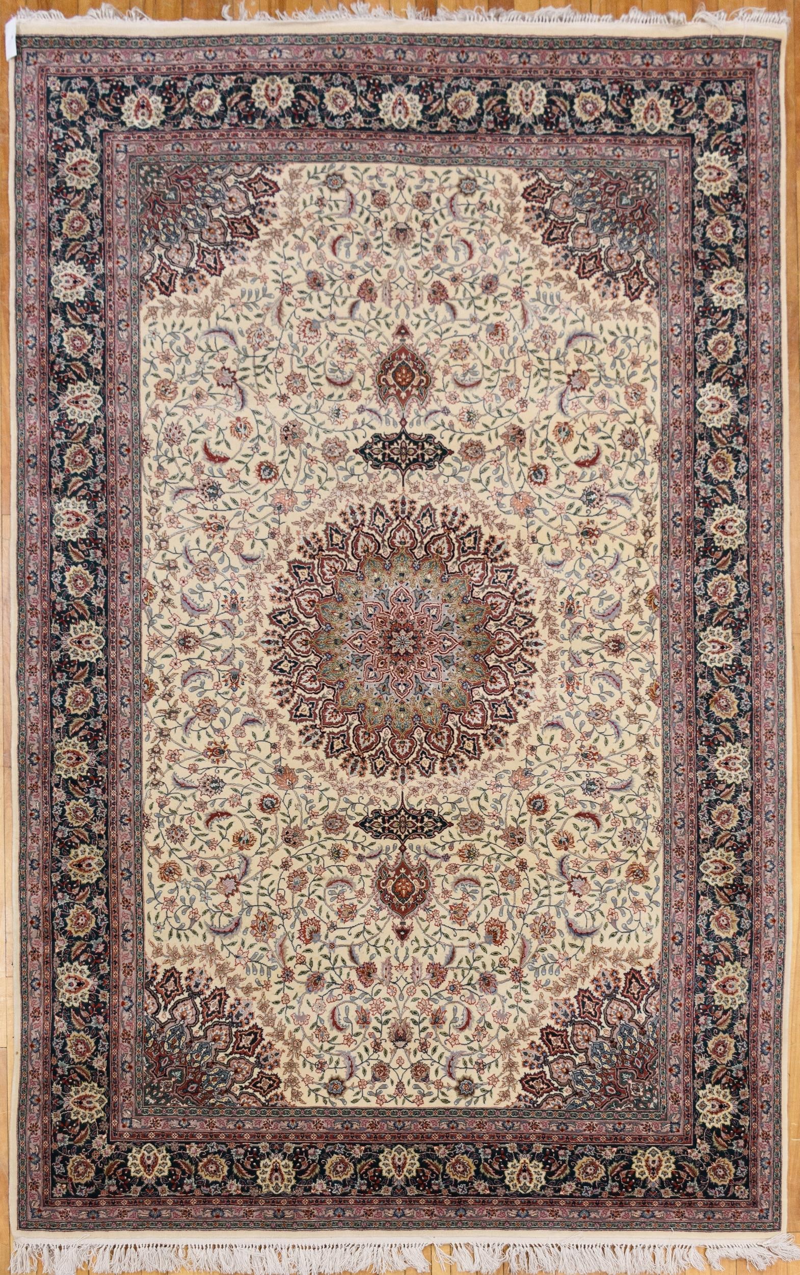FINELY WOVEN PERSIAN IVORY GROUND ORIENTAL RUG.: A finely woven Persian oriental rug, the ivory field with an allover palmette and scrolling vine design centered by a radiating floral medallion in sage, rose and burgundy, with pendants above and bel