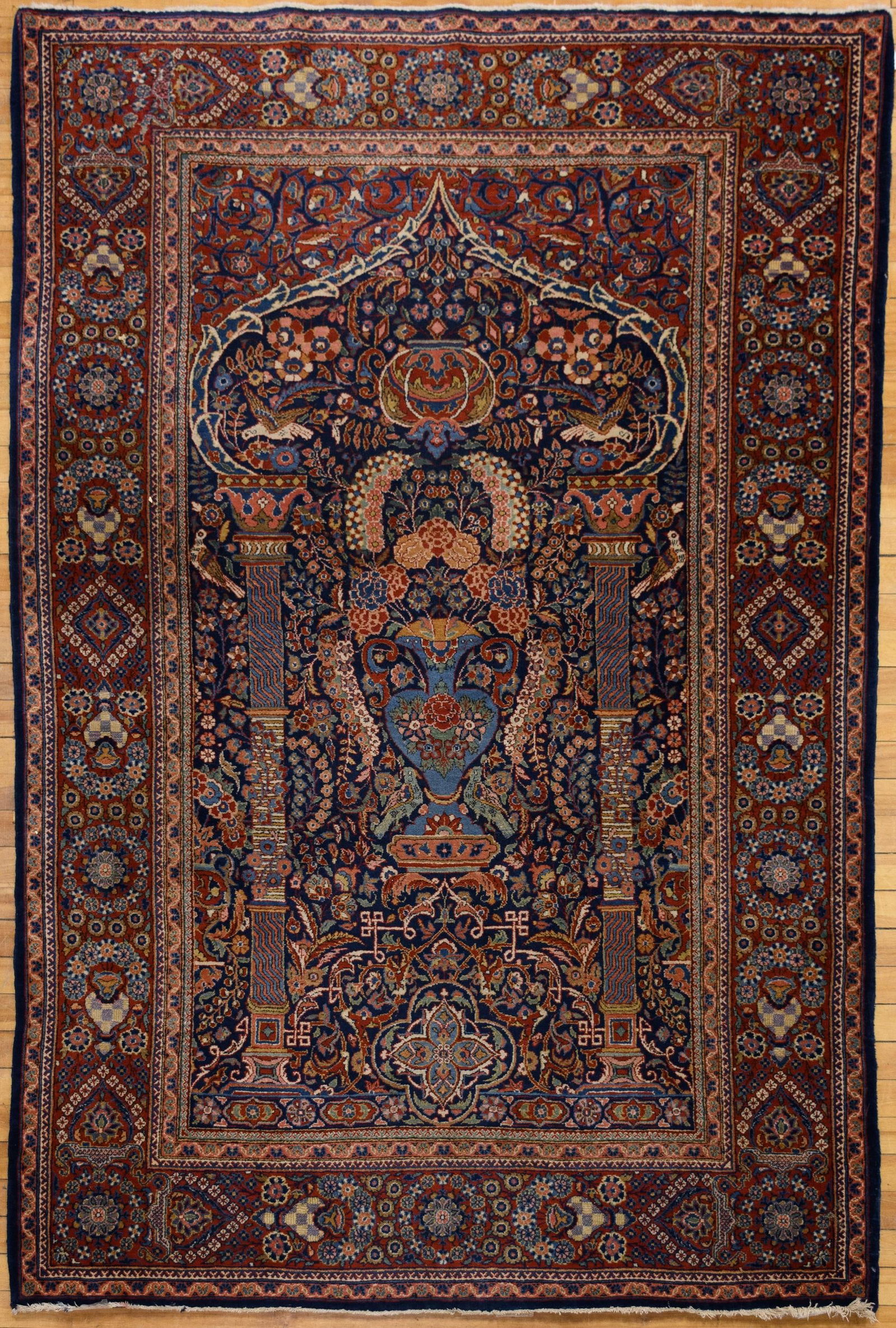 ANTIQUE PERSIAN BLUE GROUND ORIENTAL PRAYER RUG.: A ca. 1920 Persian oriental prayer rug, the midnight blue mihrab flanked by a pair of slender columns and centered by a flowering vase issuing a dense tree of life, with confronting birds in the spand