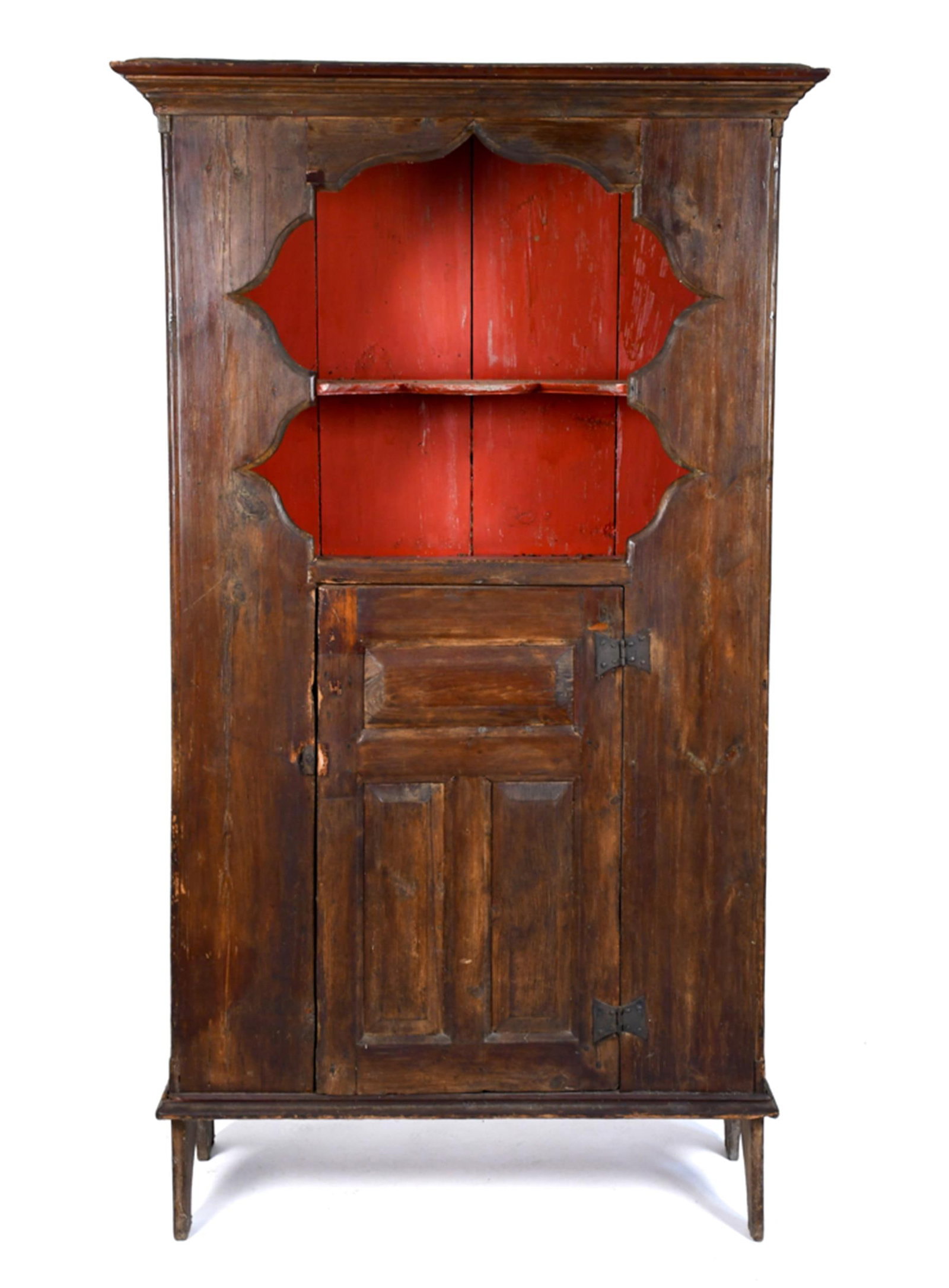 18TH C. WILLIAM AND MARY SCALLOP TOP CUPBOARD.: An 18th C. hard pine one-piece floor cupboard. A boldly molded cornice surmounts an open upper section fitted with a shaped multilobed surround and a red-painted interior with two open shelves; the