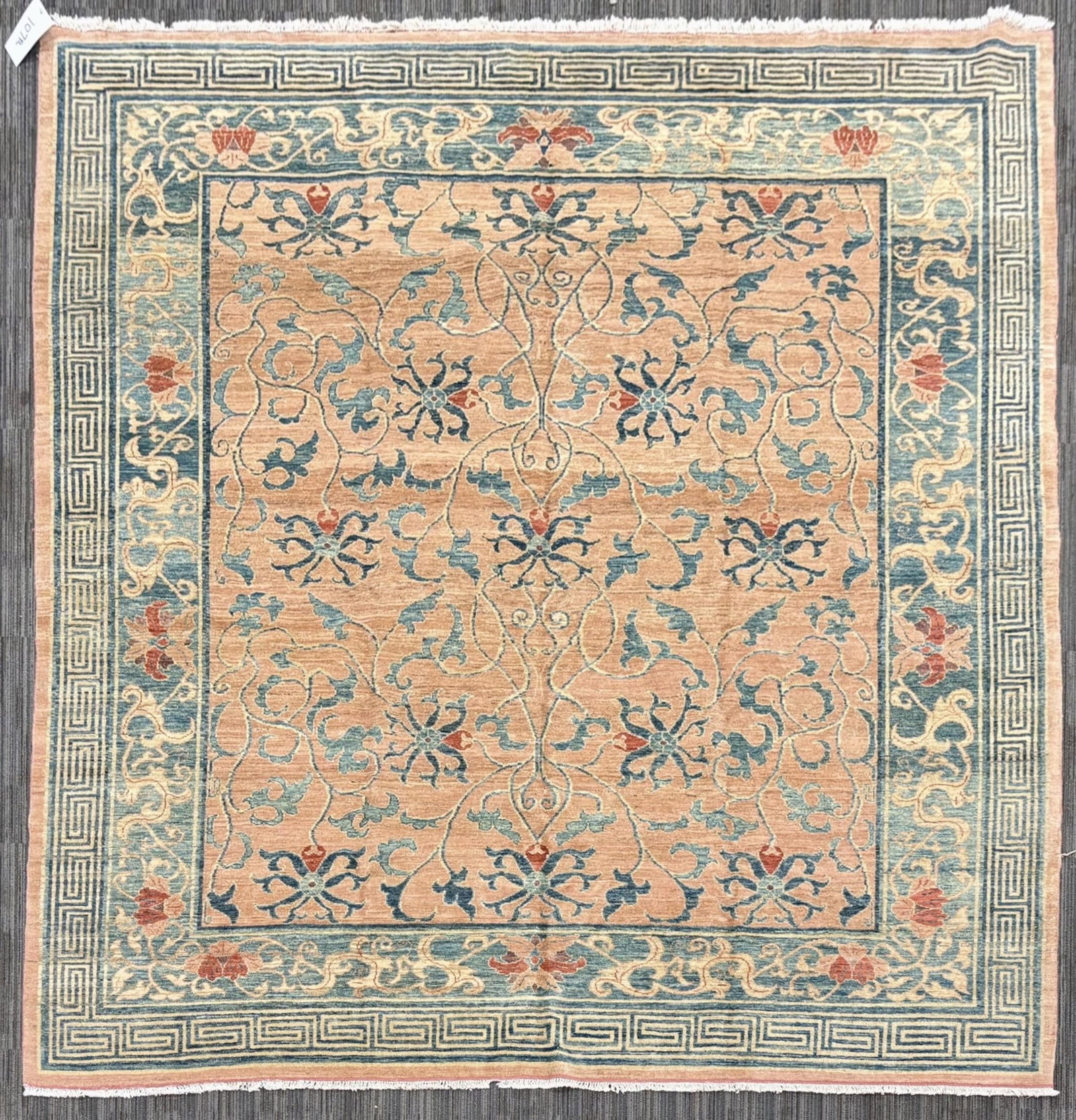 VINTAGE ORIENTAL ROOM SIZE RUG.: A vintage room size rug with a pale peach field decorated with an elegant symmetrical arrangement of scrolling floral vines and stylized blossoms in shades of teal blue and muted red. The field is