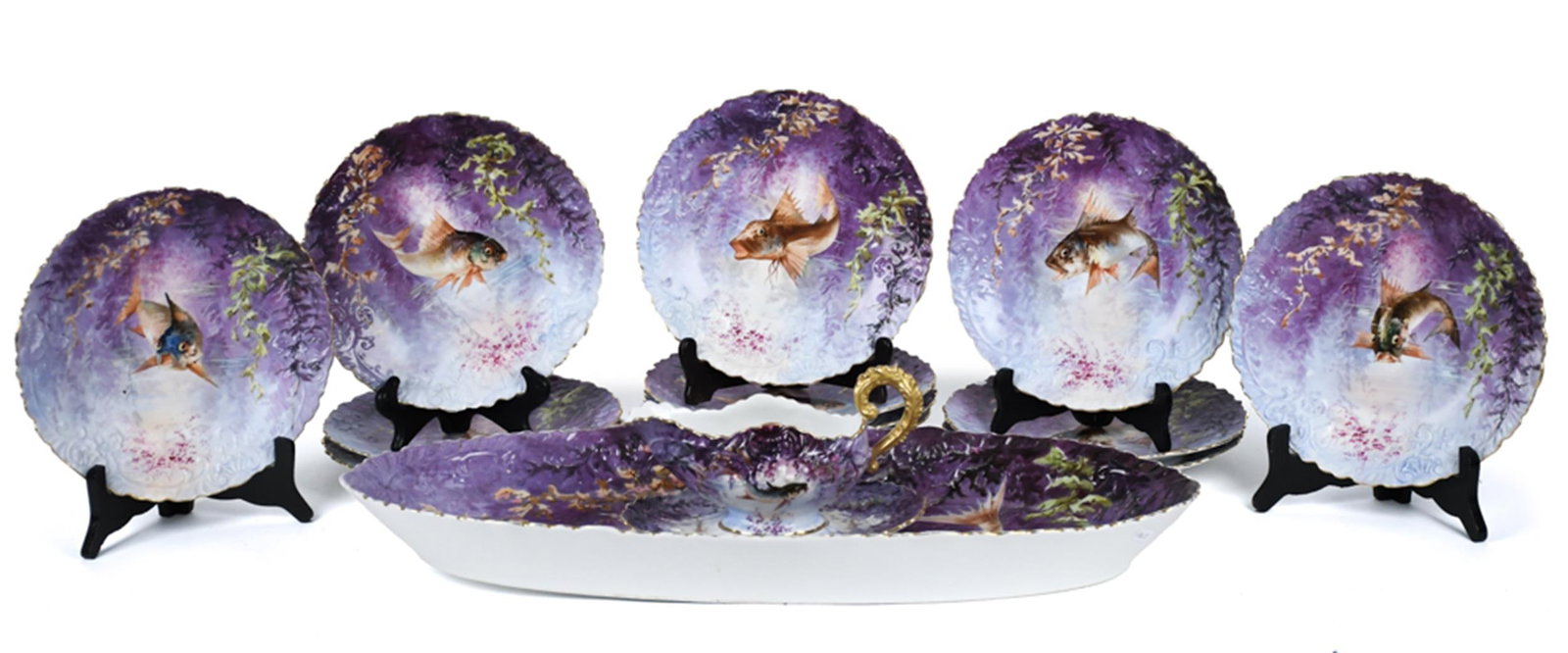 ANTIQUE FRENCH PORCELAIN FISH SET, 14 PCS: A ca. 1900 French porcelain fish service of fourteen pieces, each painted with a fish among seaweed and rockweed against a mottled violet and pale blue ground within a molded scroll and shell border