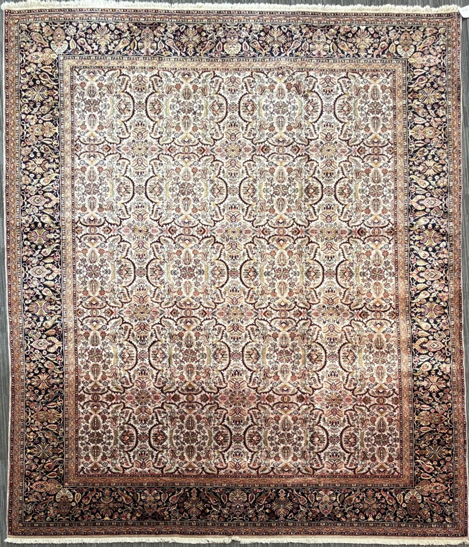 VINTAGE ORIENTAL ROOM SIZE RUG.: Vintage Oriental room size rug, with allover floral and palmette design on an ivory field, worked in muted rose, brown, tan and green tones, within a black floral main border and multiple guard border
