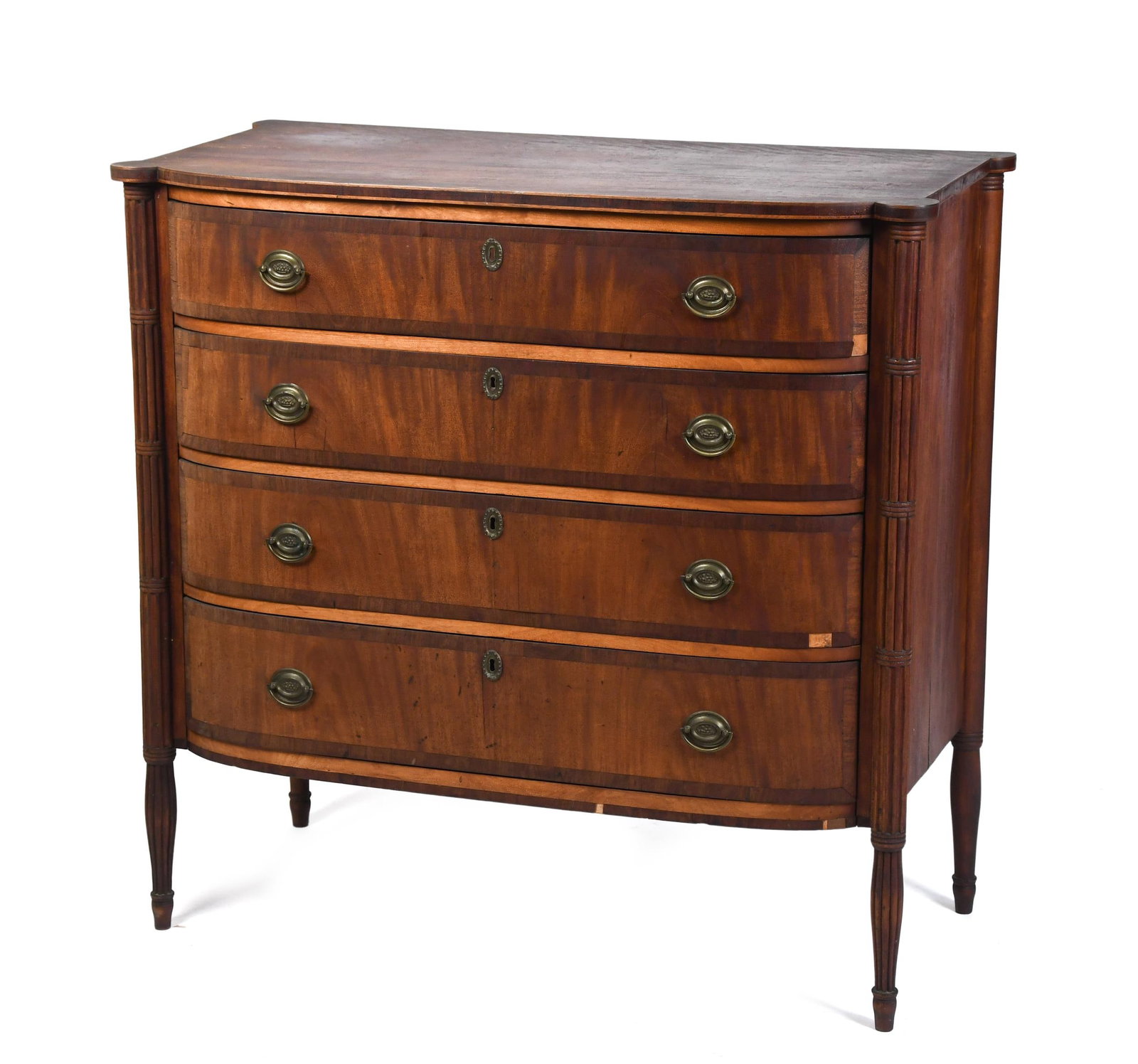 19TH C. NEW ENGLAND FEDERAL CHEST.: A ca. 1820 New England birch and mahogany veneered bow front and cookie corner Federal chest of four drawers, flanked by carved columns and elevated on reeded/tapered legs. Chest in old surface with