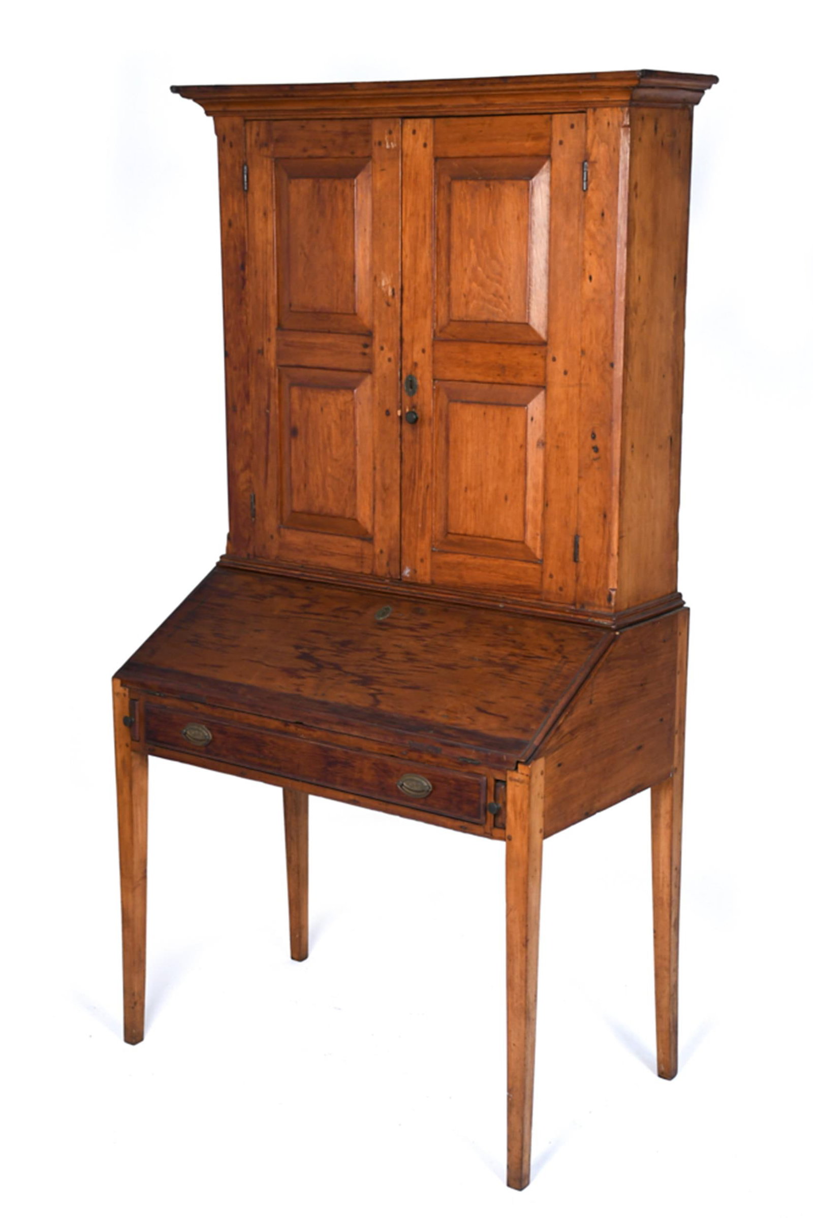 19TH C. COUNTRY ANTIQUE PINE SECRETARY.: A single-part American country pine secretary desk. Upper bookcase with paneled doors, over desk with hinged and slanted lid, fitted desk interior, on high tapered legs. 69.5”H x 36”W x