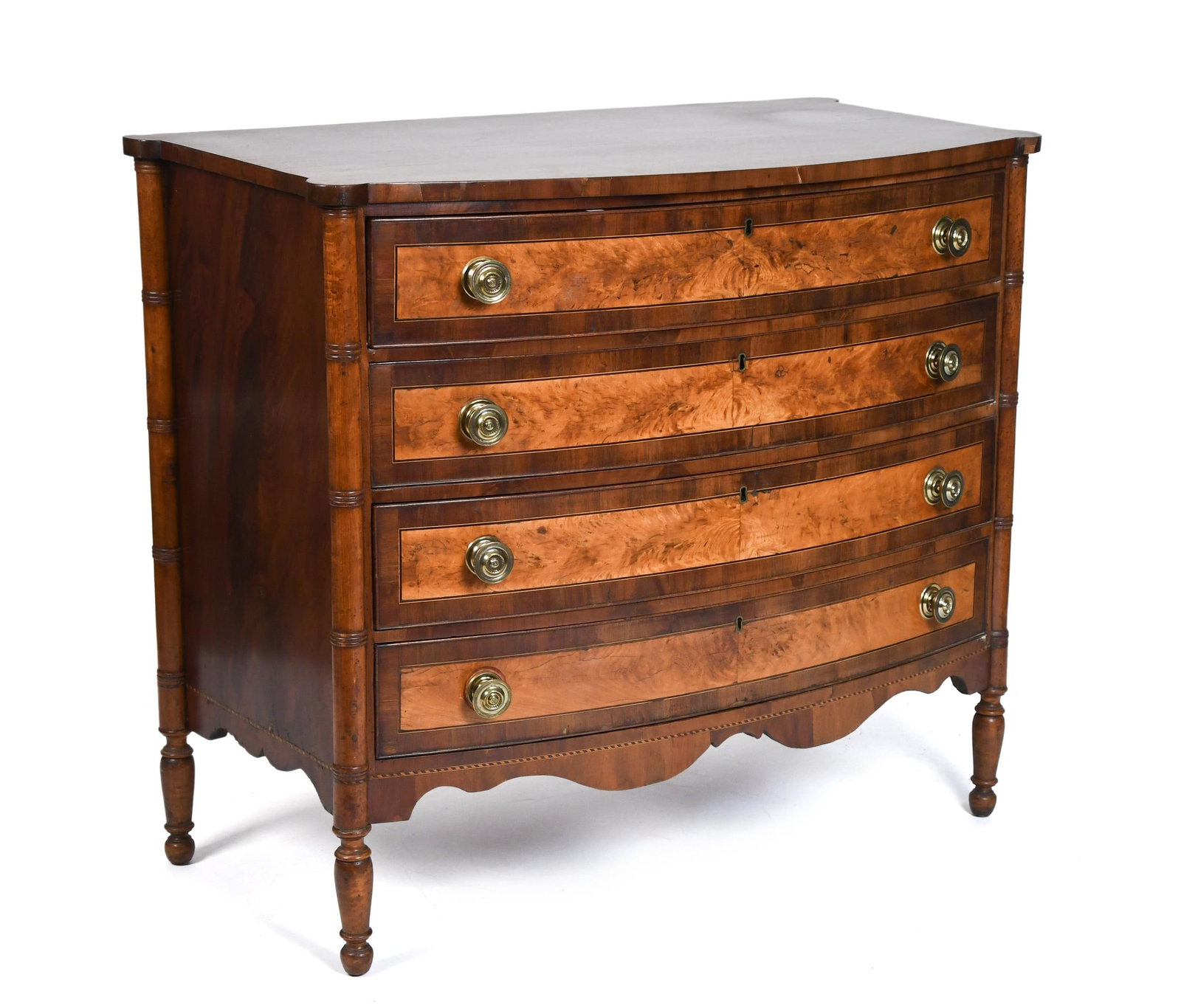 19TH C. AMERICAN FEDERAL CHEST.: A ca. 1810 New England Federal cherry chest with turret shaped top over bow-front case front containing four mahogany and flame birch veneers, on turned legs. 38.5”H x 42:W x 23”D.