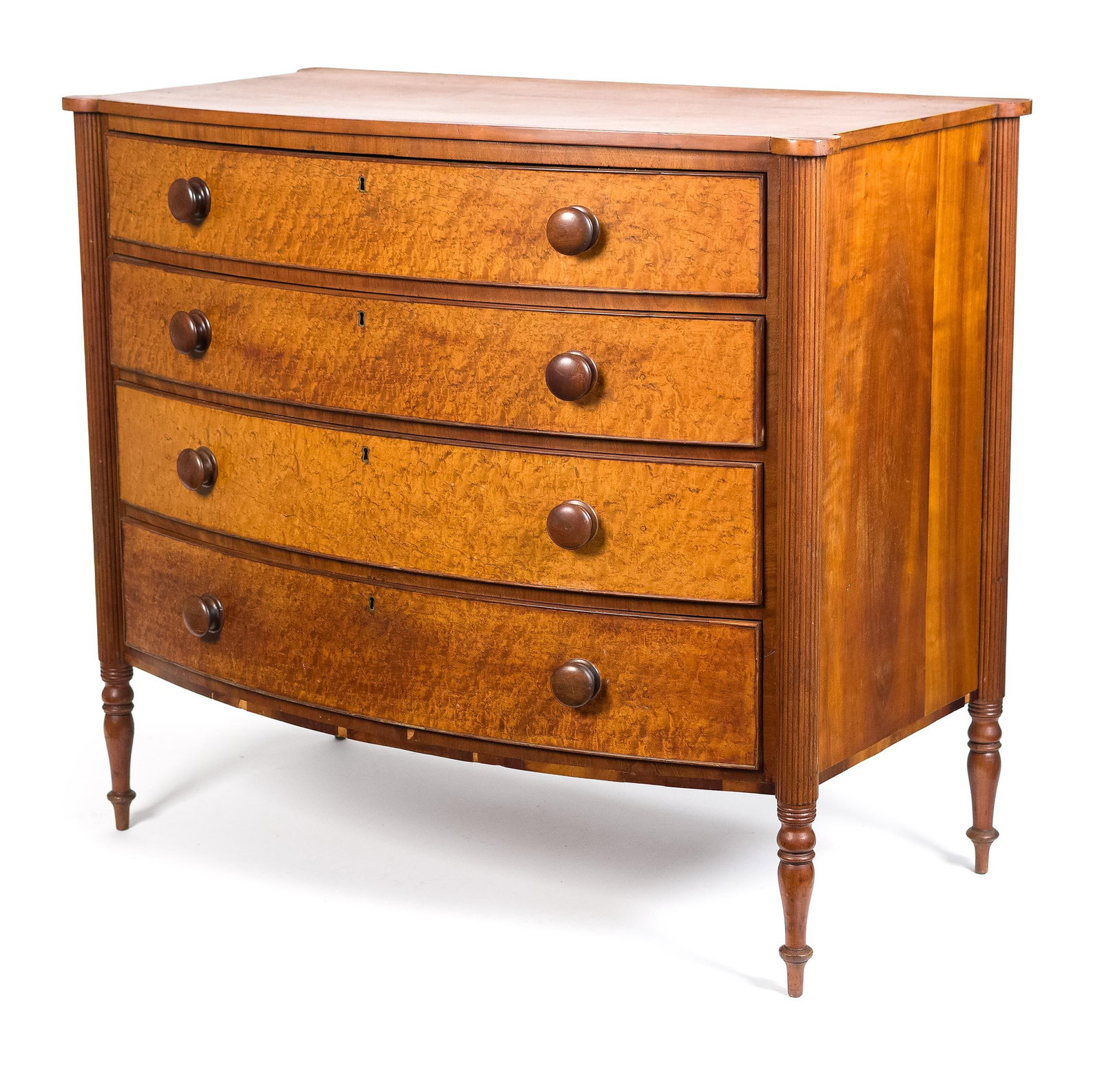 19TH C. NE FEDERAL CHERRY AND BIRDSEYE CHEST.: A ca. 1810 New England cherry chest with turret shaped top over four cock beaded bow front drawers, flanked by reeded columns and raised on turned feet. 37.5”H x 40”W x 22.5”D.